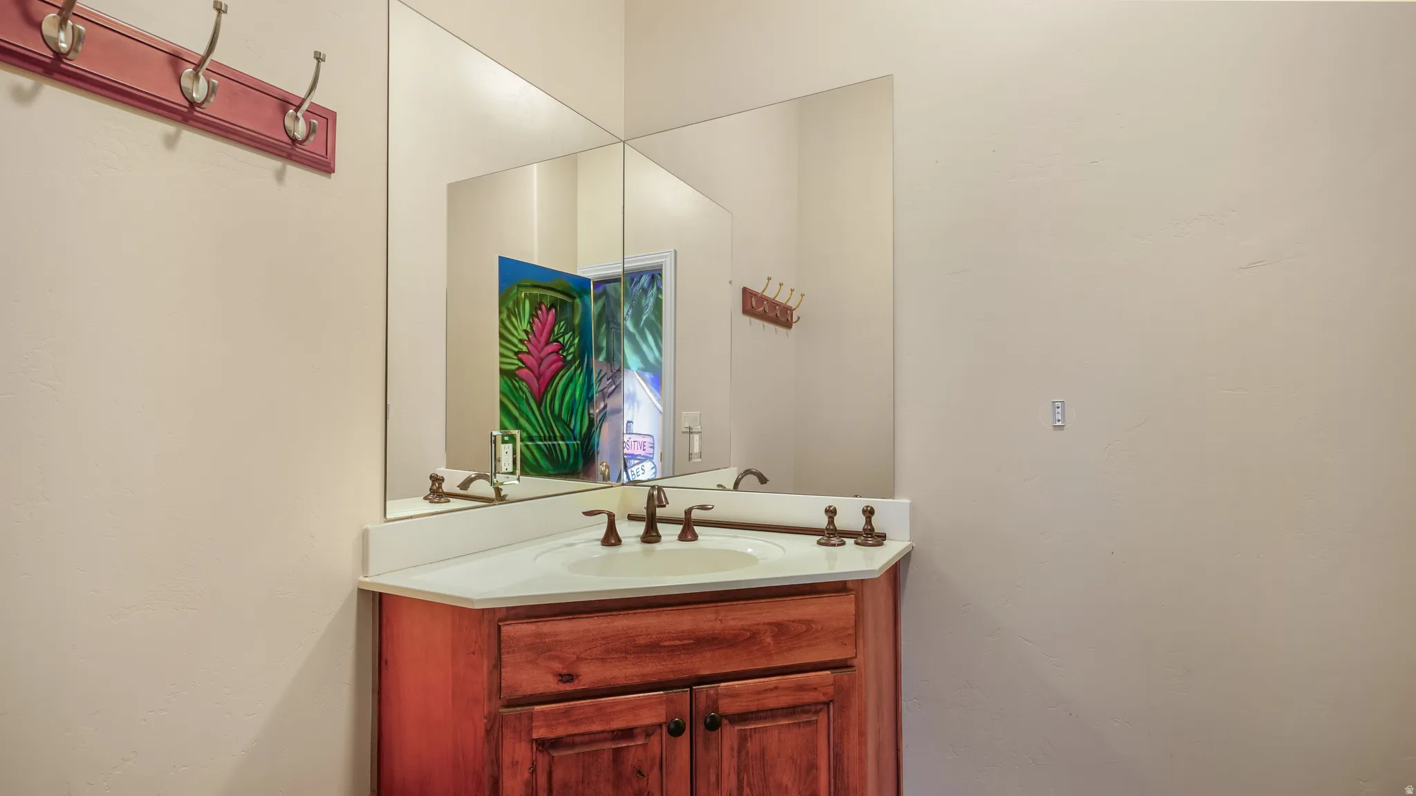 Corner vanity featuring a wood-finish cabinet, white countertop, and integrated sink