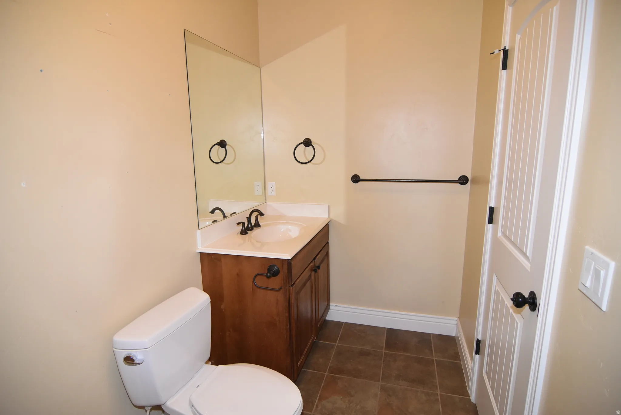 Functional powder room featuring a wooden vanity with white countertop, integrated sink, and dark bronze fixtures