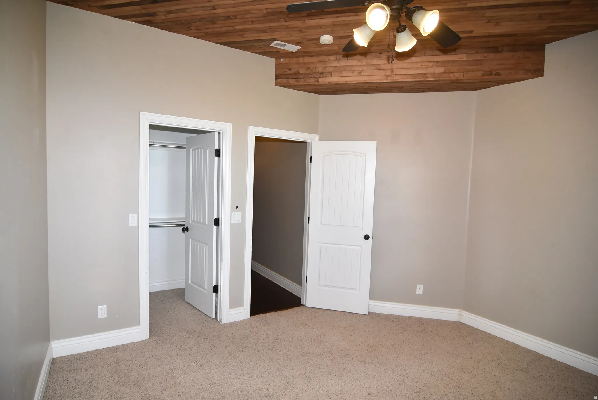 Interior space featuring a wood-finish vaulted ceiling with a ceiling fan light fixture, neutral wall paint, and plush carpeting
