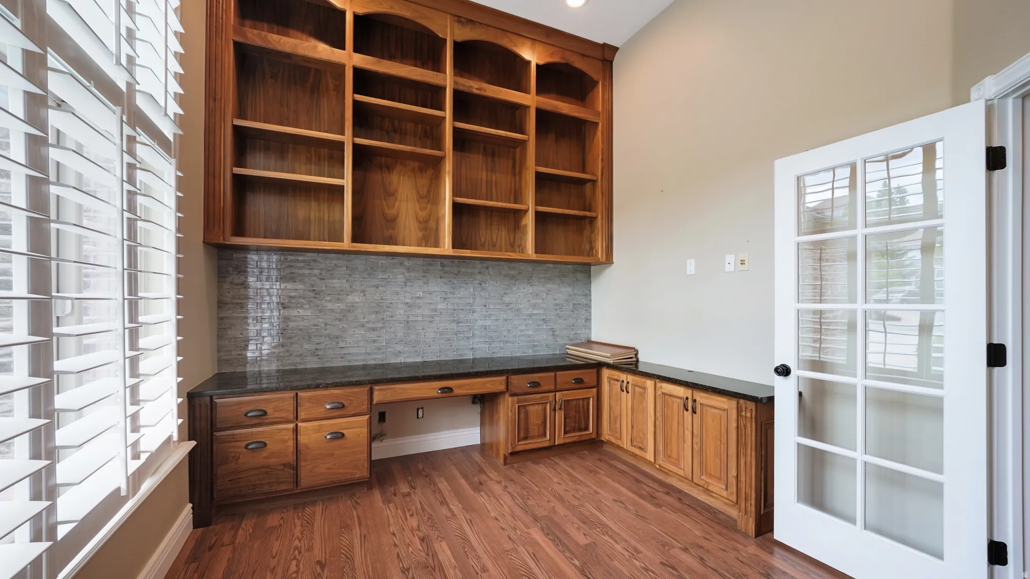 Built-in wood cabinetry with integrated desk space, dark countertops, and a tiled backsplash