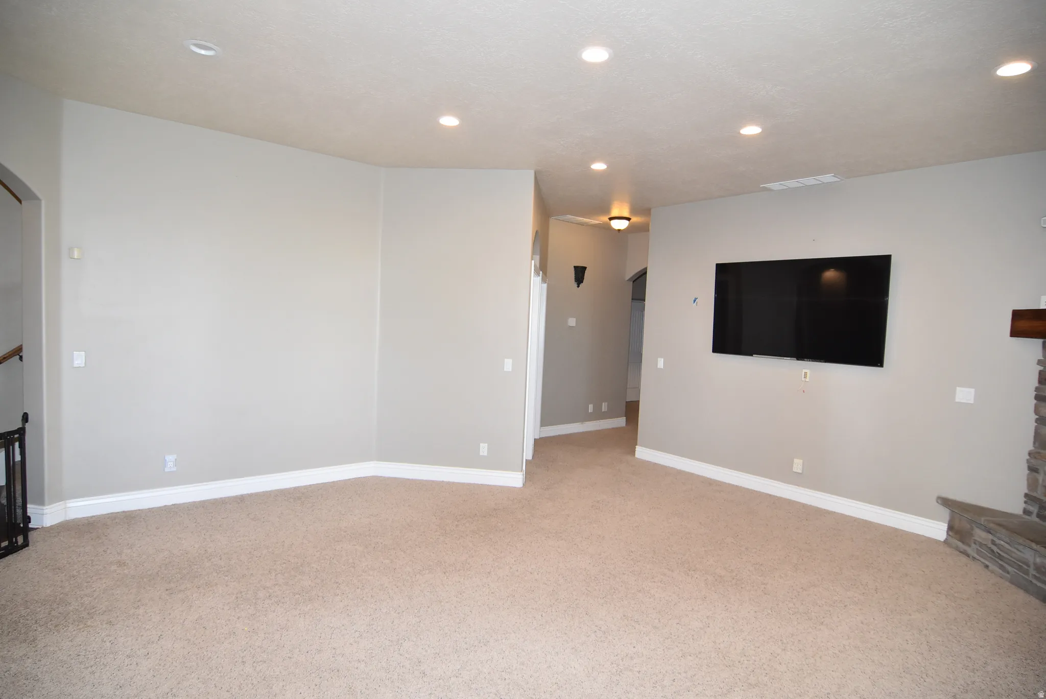 Spacious living area featuring neutral carpeting, light gray walls, white baseboards, and recessed ceiling lighting