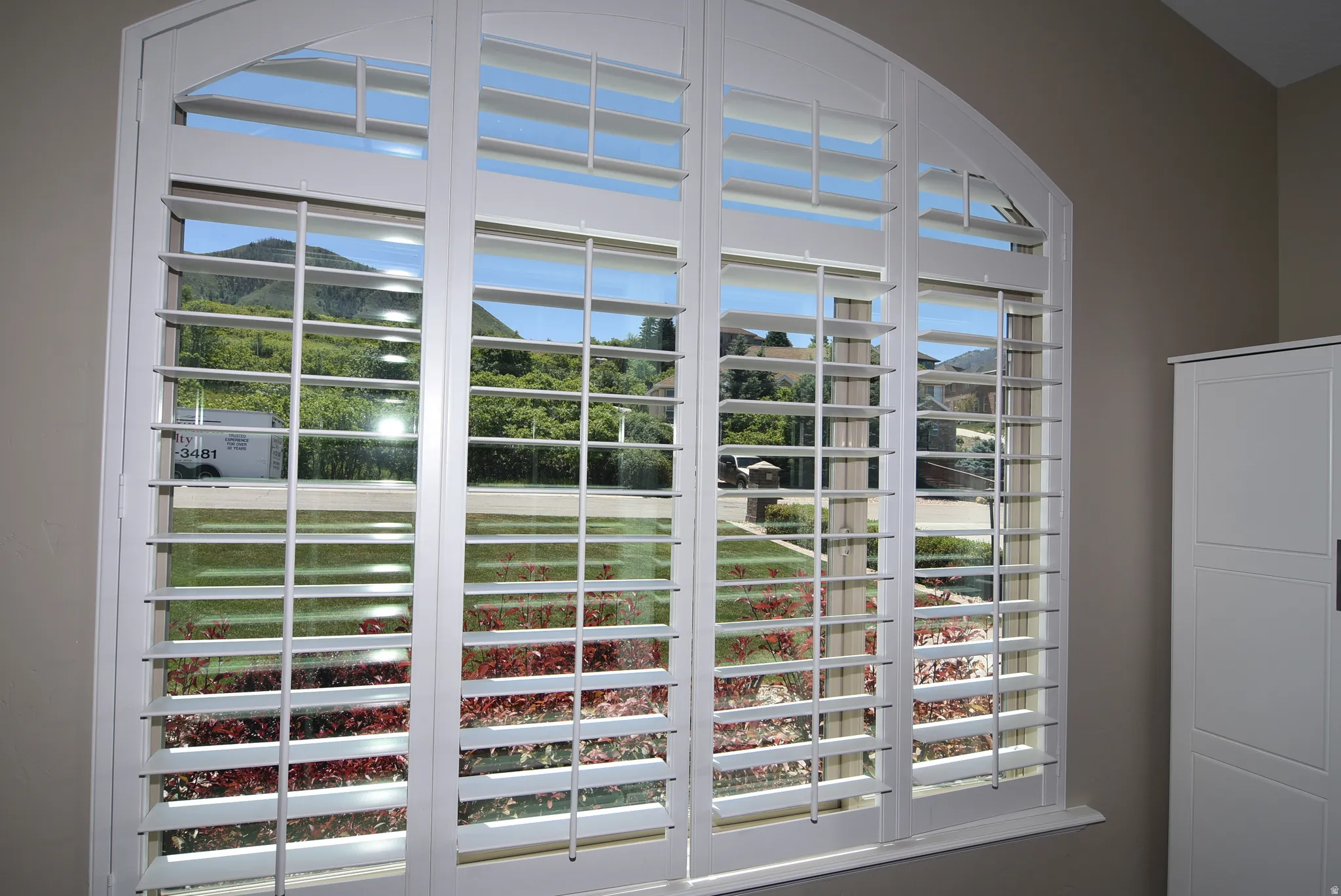 Arched window featuring white plantation shutters