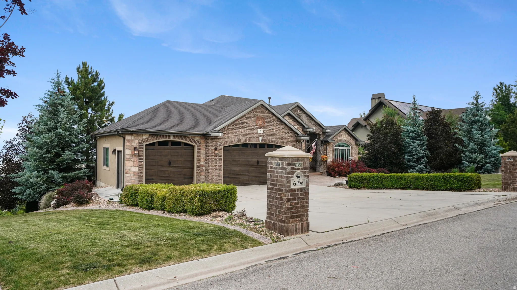 Expansive residential exterior featuring a multi-tone brick and stucco facade, a multi-car driveway, and a manicured lawn with mature landscaping