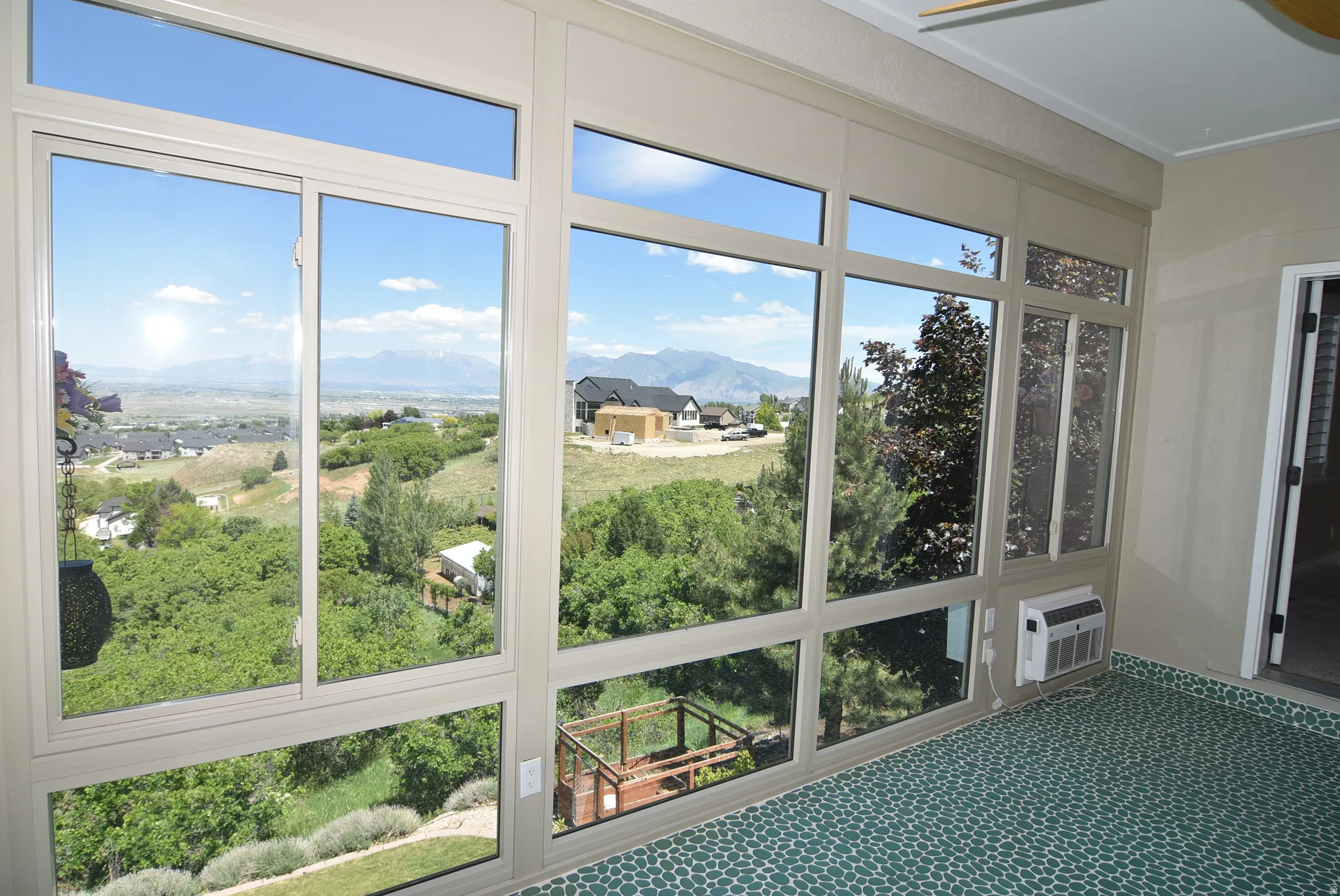 Sunroom featuring expansive multi-pane windows, a ceiling fan, and a wall-mounted air conditioning unit