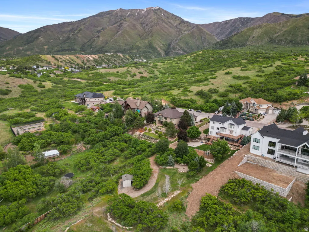 Expansive property situated against a mountainous backdrop, featuring a mix of mature trees and open green spaces