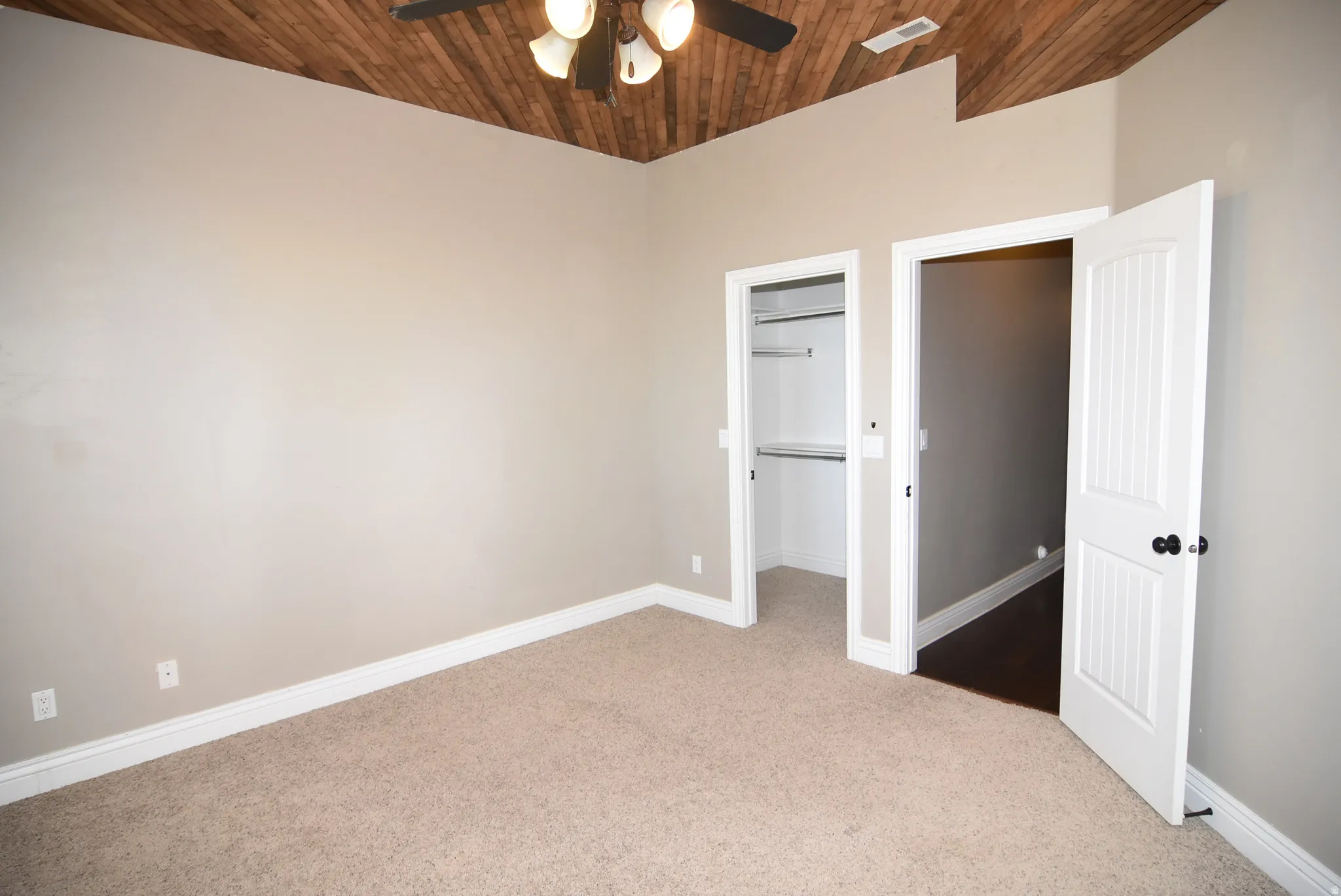 Room featuring a wood-finish vaulted ceiling, ceiling fan with integrated lighting, neutral carpet, and two white panel doors