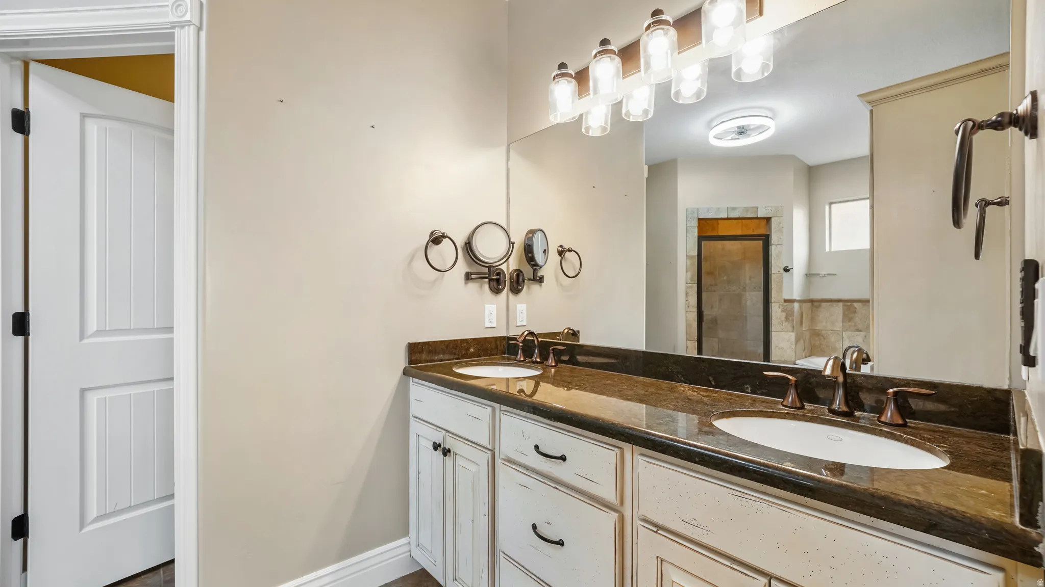Dual vanity featuring an expansive mirror, brown patterned countertop, and undermount sinks