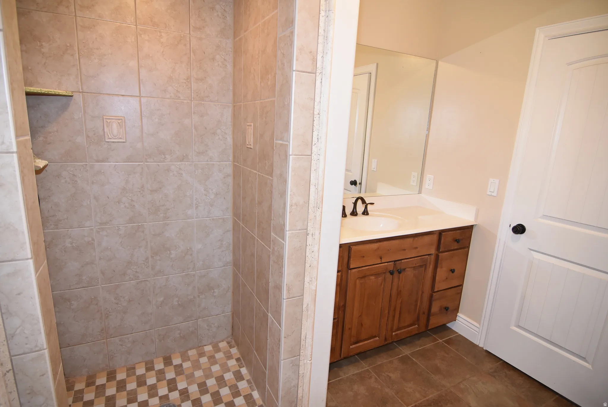 Tiled shower enclosure featuring a checkered floor pattern and an integrated corner shelf