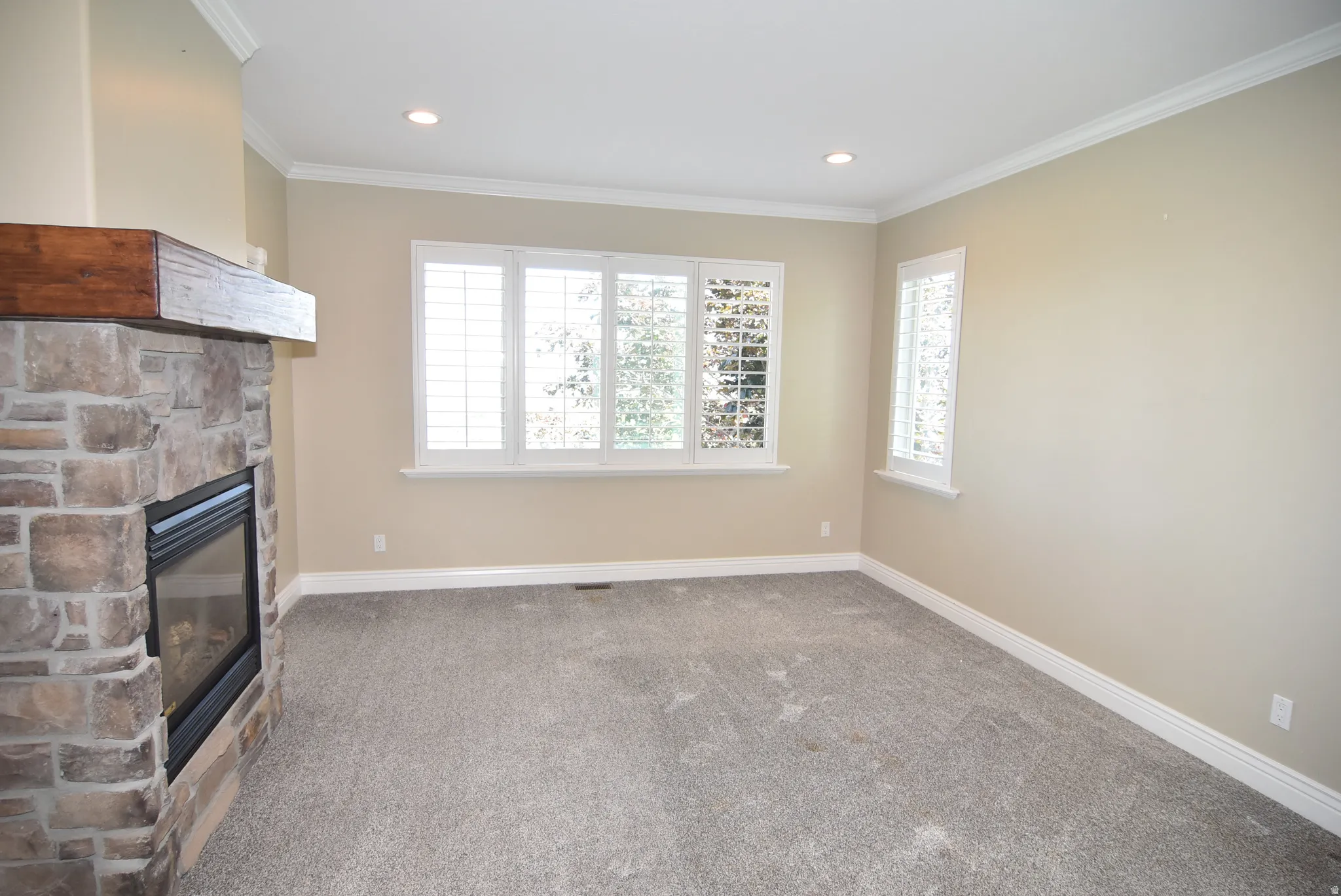 Owner's Bedroom space featuring a stone-clad fireplace with a wood-finish mantel, recessed lighting, and crown molding