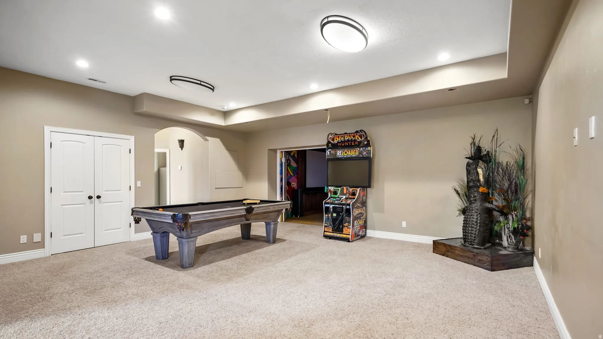 Spacious room featuring neutral carpeting, recessed lighting, and a tray ceiling
