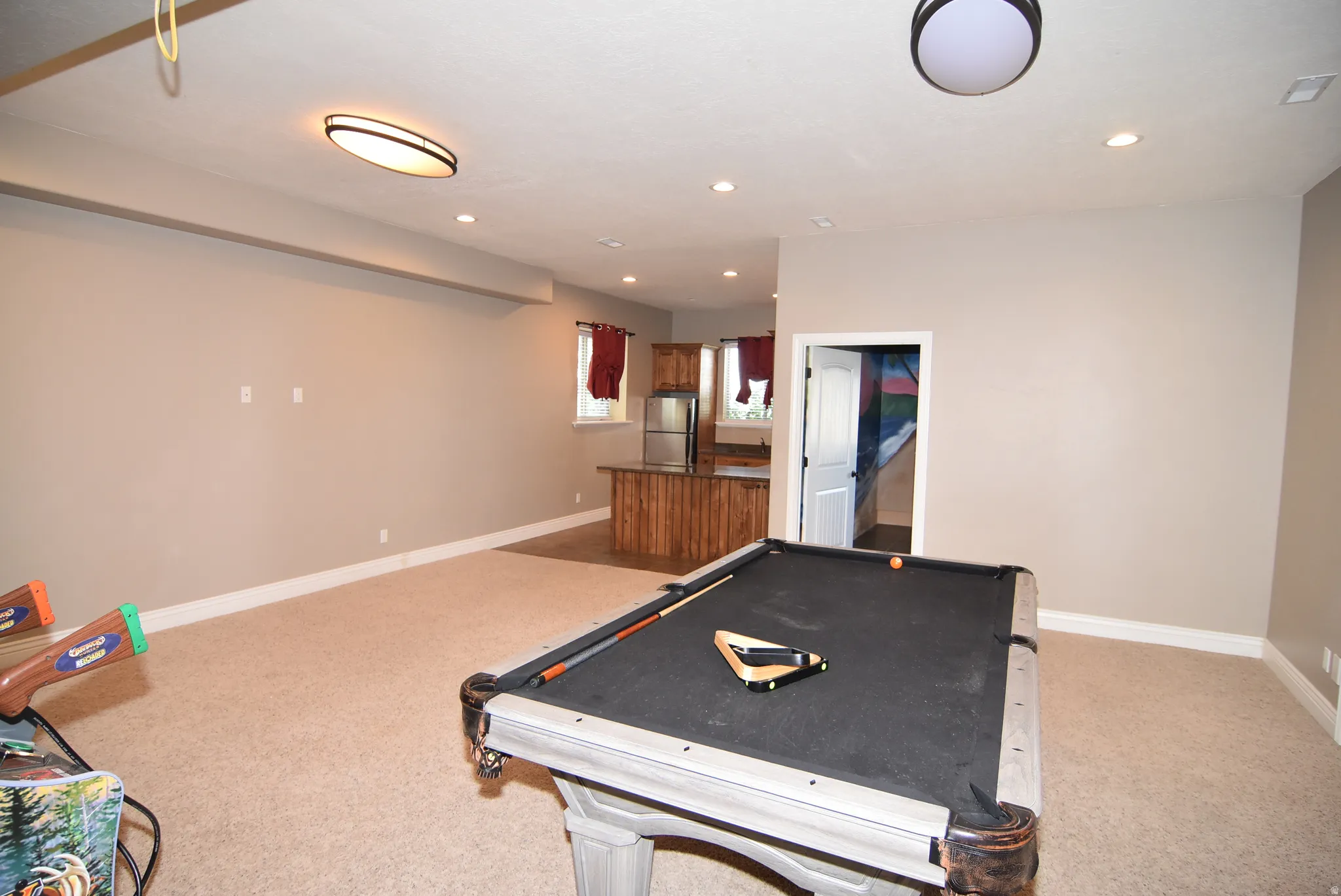Carpeted recreation area featuring recessed lighting, a built-in wet bar with wood cabinetry, and a full-size billiards table