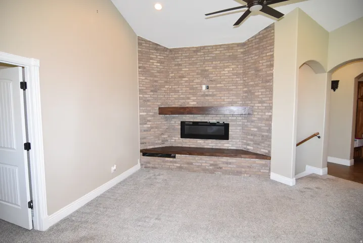 Living space featuring a corner brick fireplace with a wood mantel and hearth