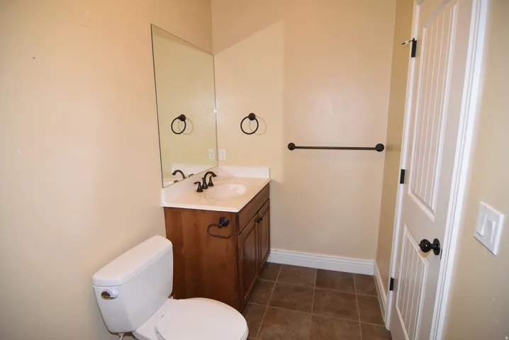 Functional powder room featuring a wooden vanity with white countertop, integrated sink, and dark bronze fixtures