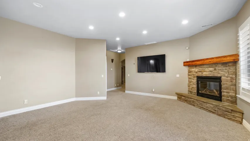 Spacious living area featuring a corner stone fireplace with a substantial wood mantel
