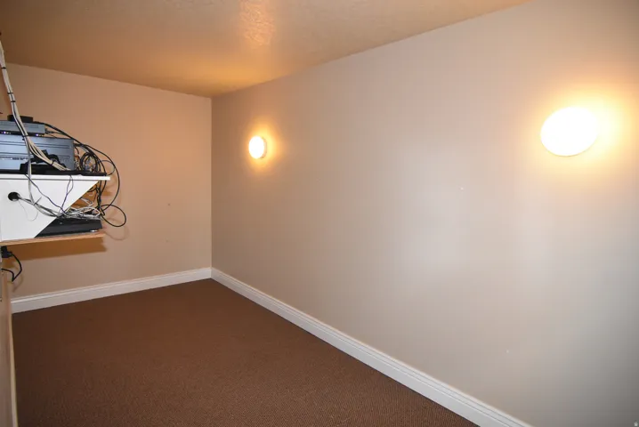 AV equipment inCarpeted room featuring neutral wall paint, white baseboards, and two wall-mounted circular light fixtures