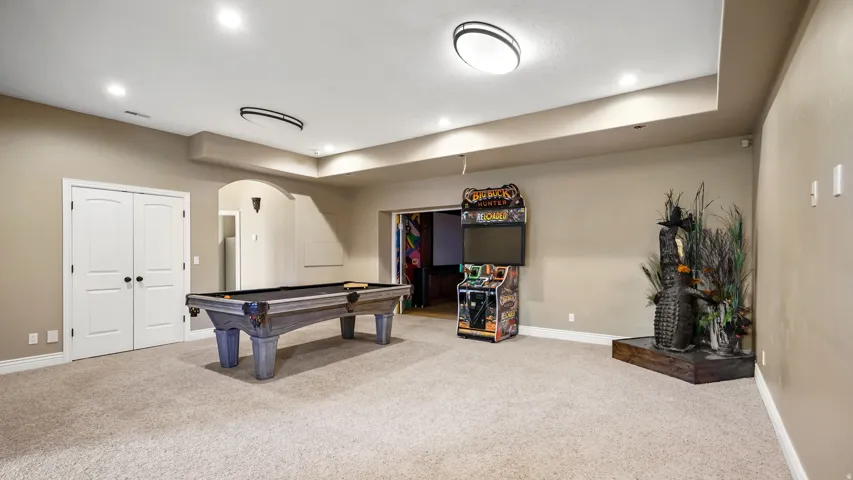 Spacious room featuring neutral carpeting, recessed lighting, and a tray ceiling