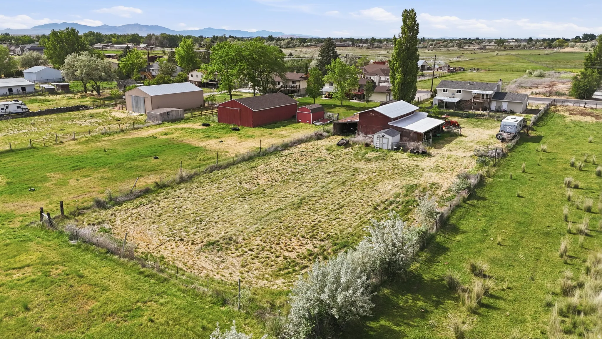 Expansive green spaces featuring multiple outbuildings, fencing, and distant mountain ranges