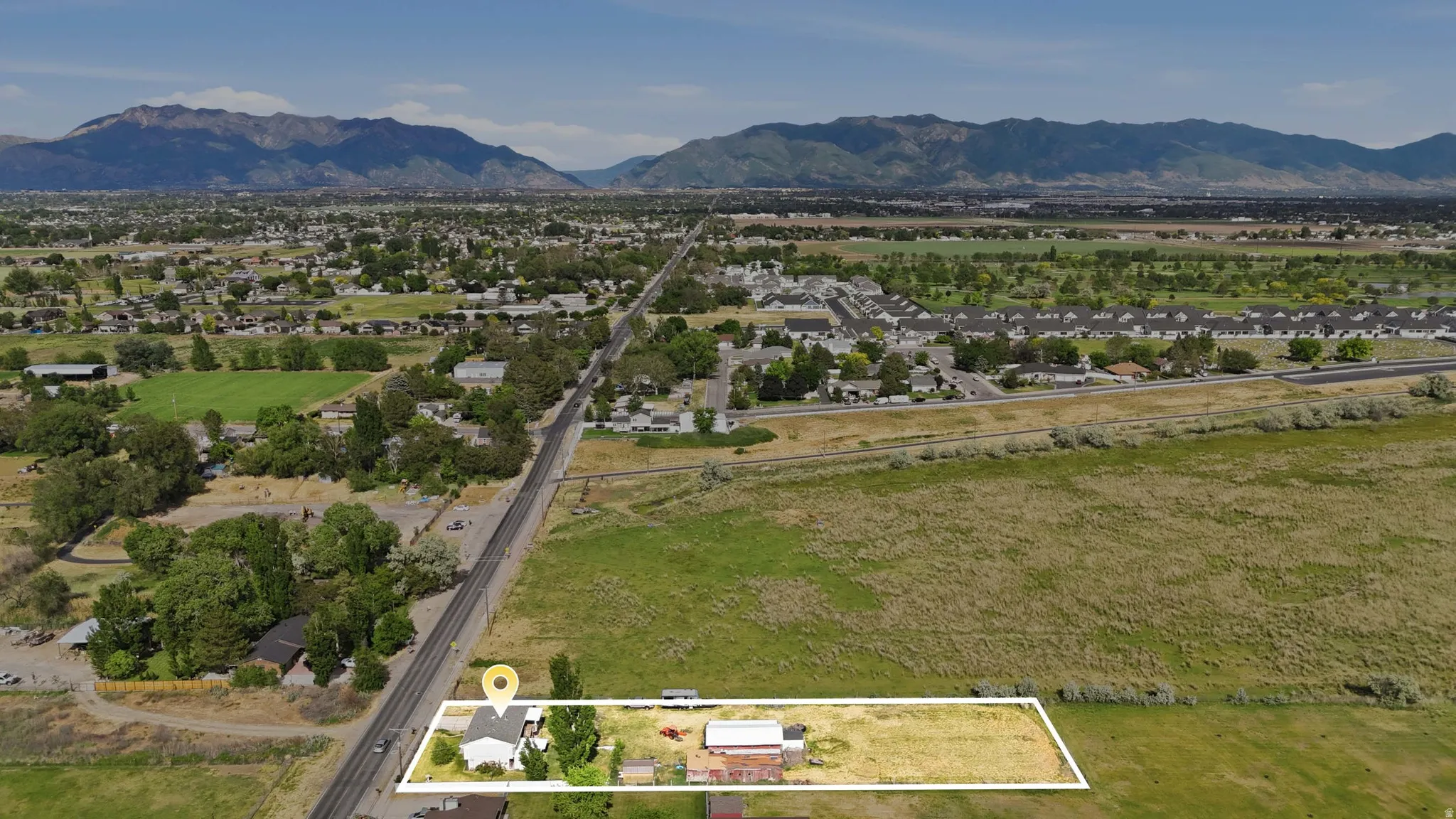 Expansive aerial perspective showcasing a property outlined in white, featuring a single-story residence with a light-colored roof