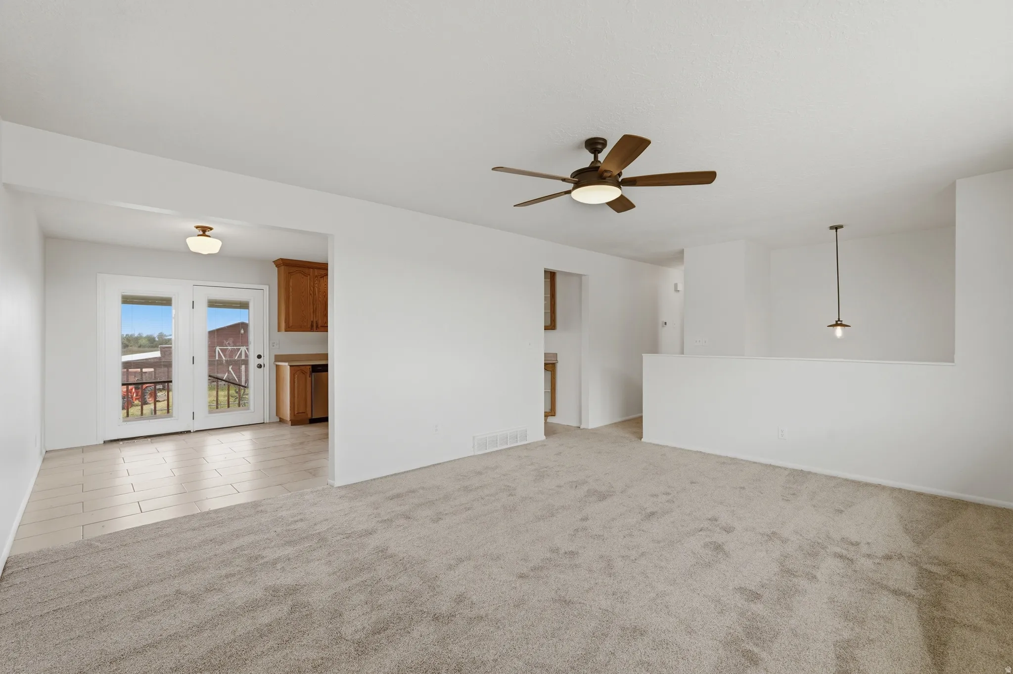 Spacious living area featuring neutral carpeting and a ceiling fan with integrated lighting