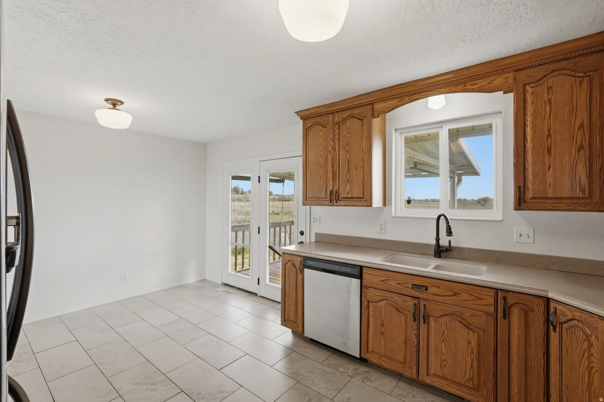Kitchen featuring light wood cabinetry, light-toned countertops, and a double basin sink with a matte black faucet