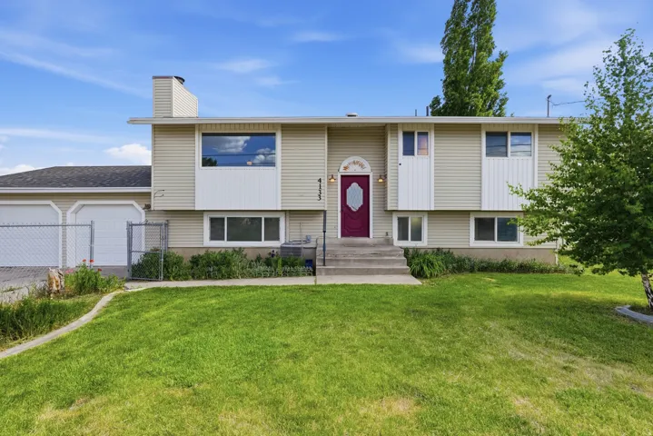 Split-level residence featuring light-colored siding and a contrasting red entry door with decorative glass