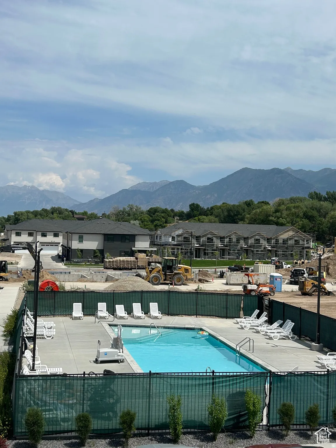 Outdoor swimming pool with concrete decking, perimeter fencing, and lounge chairs