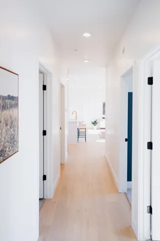 Hallway featuring light wood-finish flooring, recessed ceiling lighting, crisp white walls, and white trim