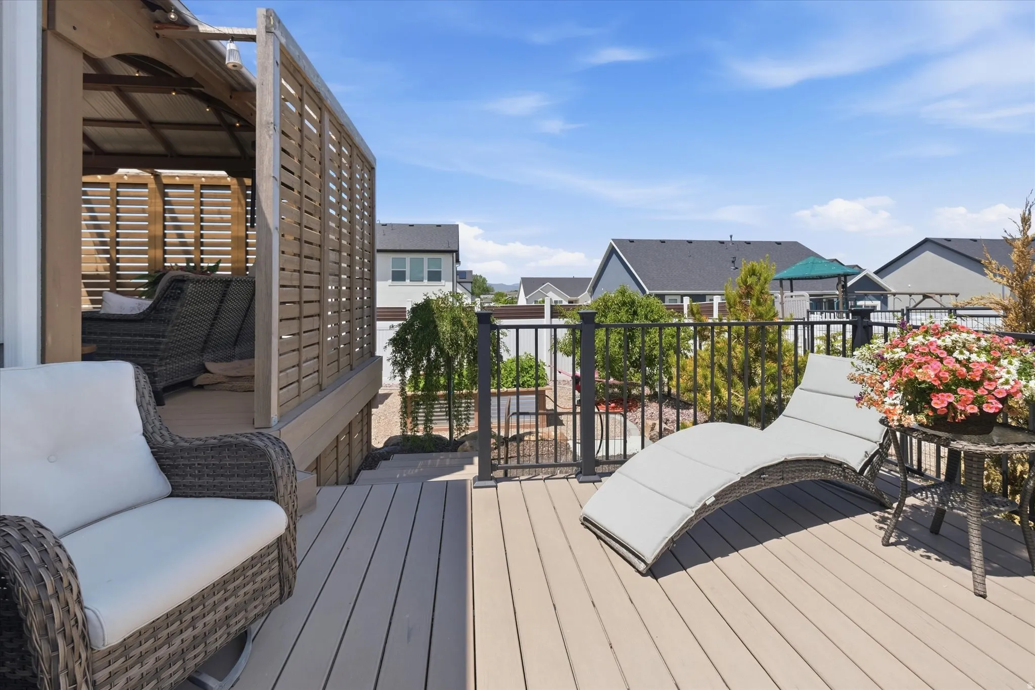 Expansive multi-level deck featuring composite decking, black metal railings, and a built-in pergola with louvered privacy screens