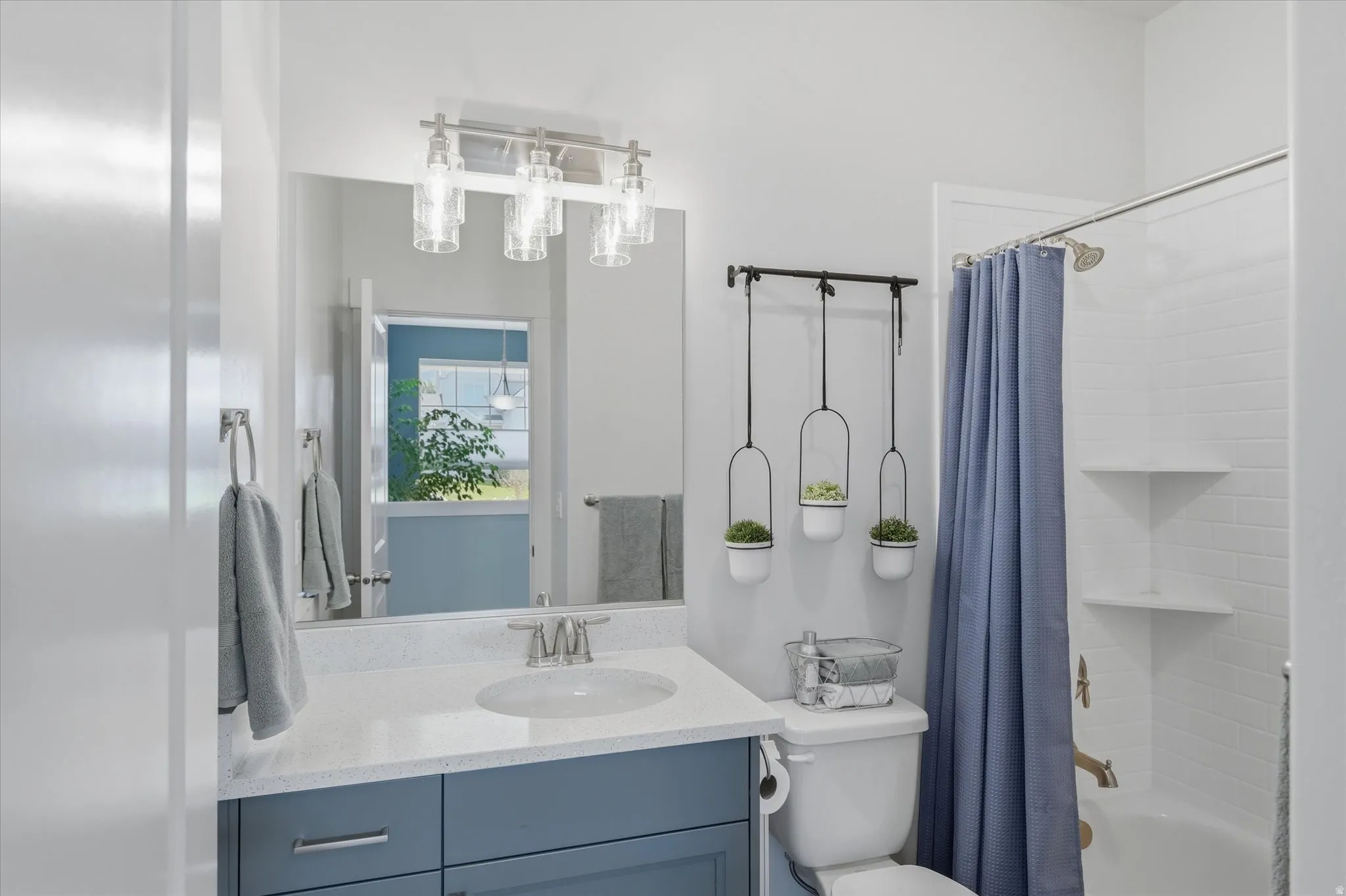 Bathroom vanity featuring a light-toned countertop, undermount sink, brushed nickel faucet, and blue cabinetry