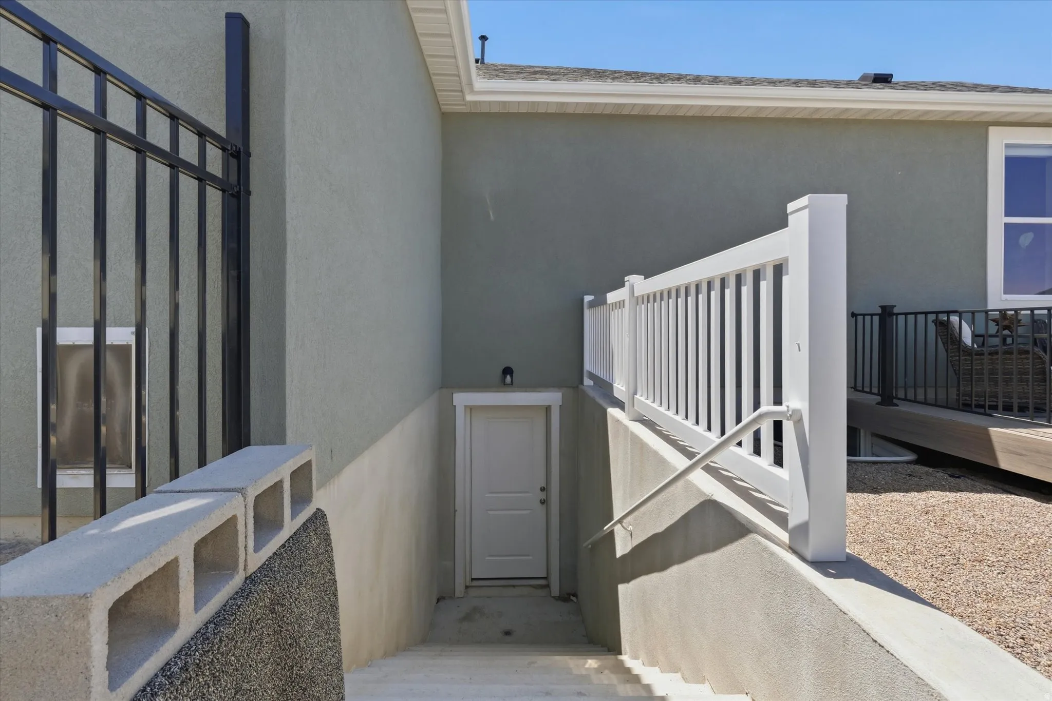 Apartment Entrance -Below-grade entry with exterior stucco finish, white railing, and exterior wall sconce