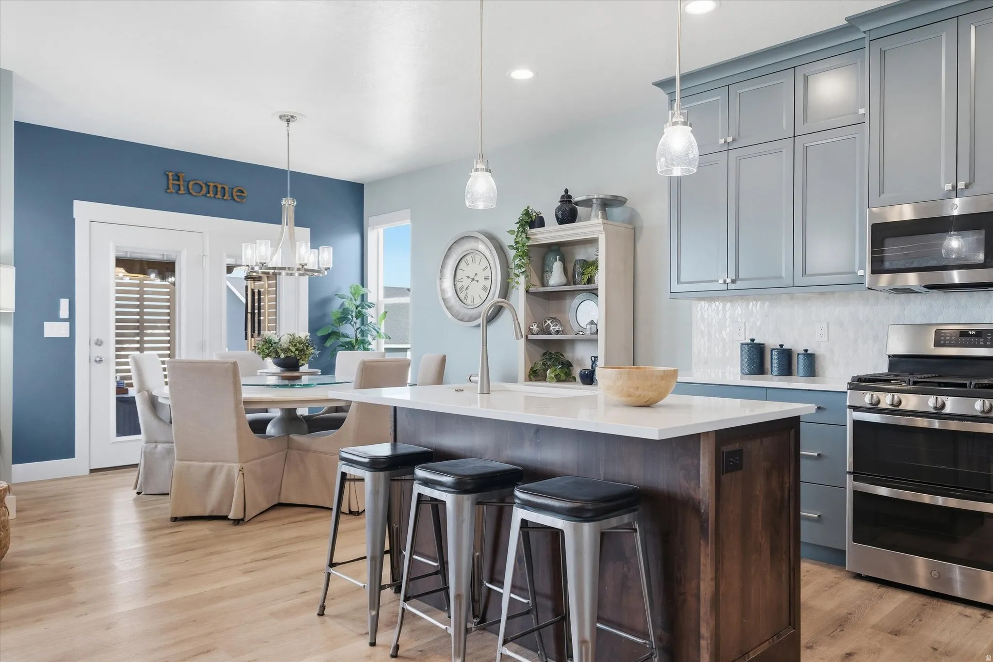 Kitchen featuring a center island with a light-toned countertop, wood-finish flooring, stainless steel appliances, and blue cabinetry