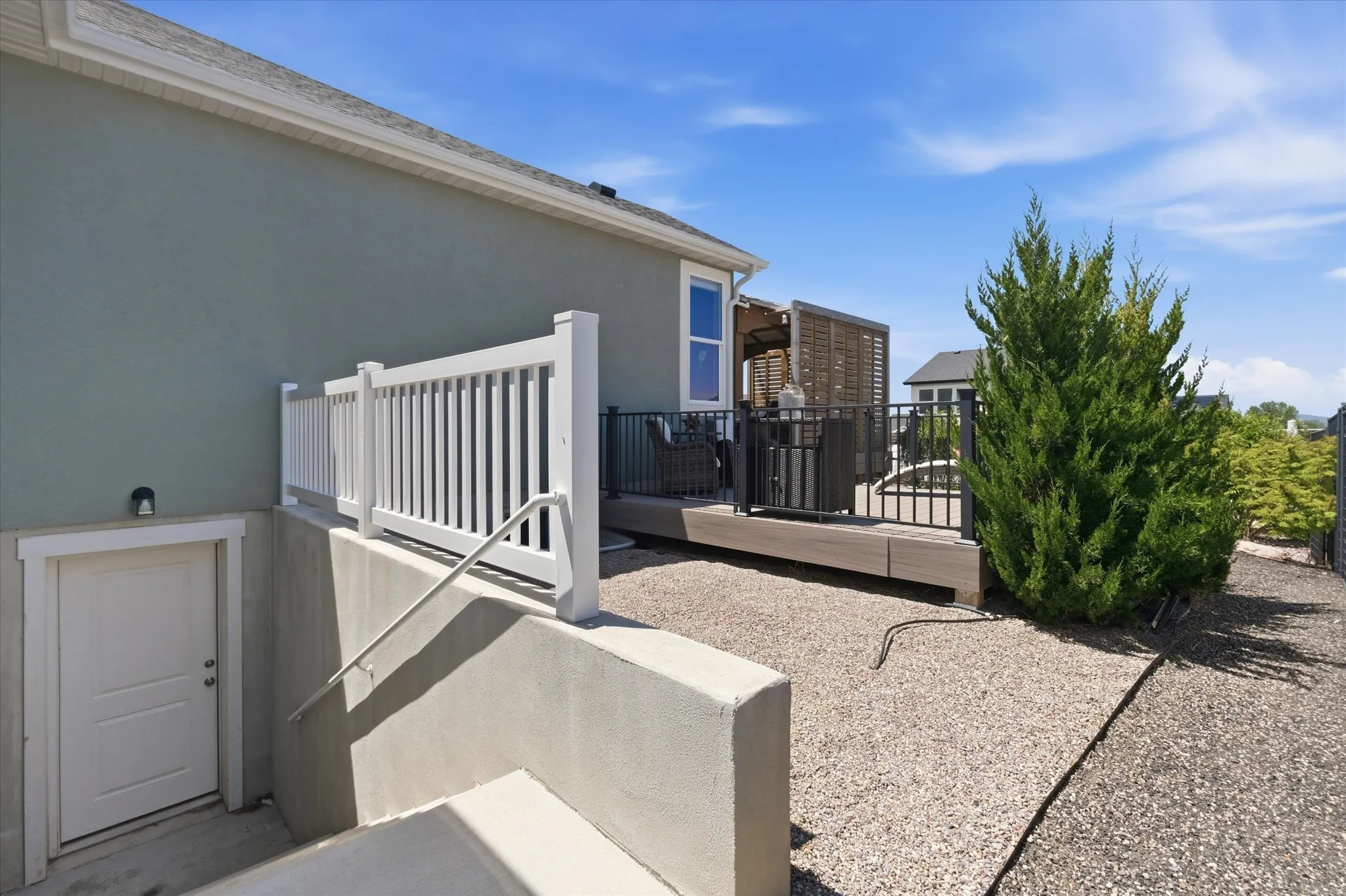 Exterior deck featuring black metal railing and a privacy screen, complemented by a gravel ground cover