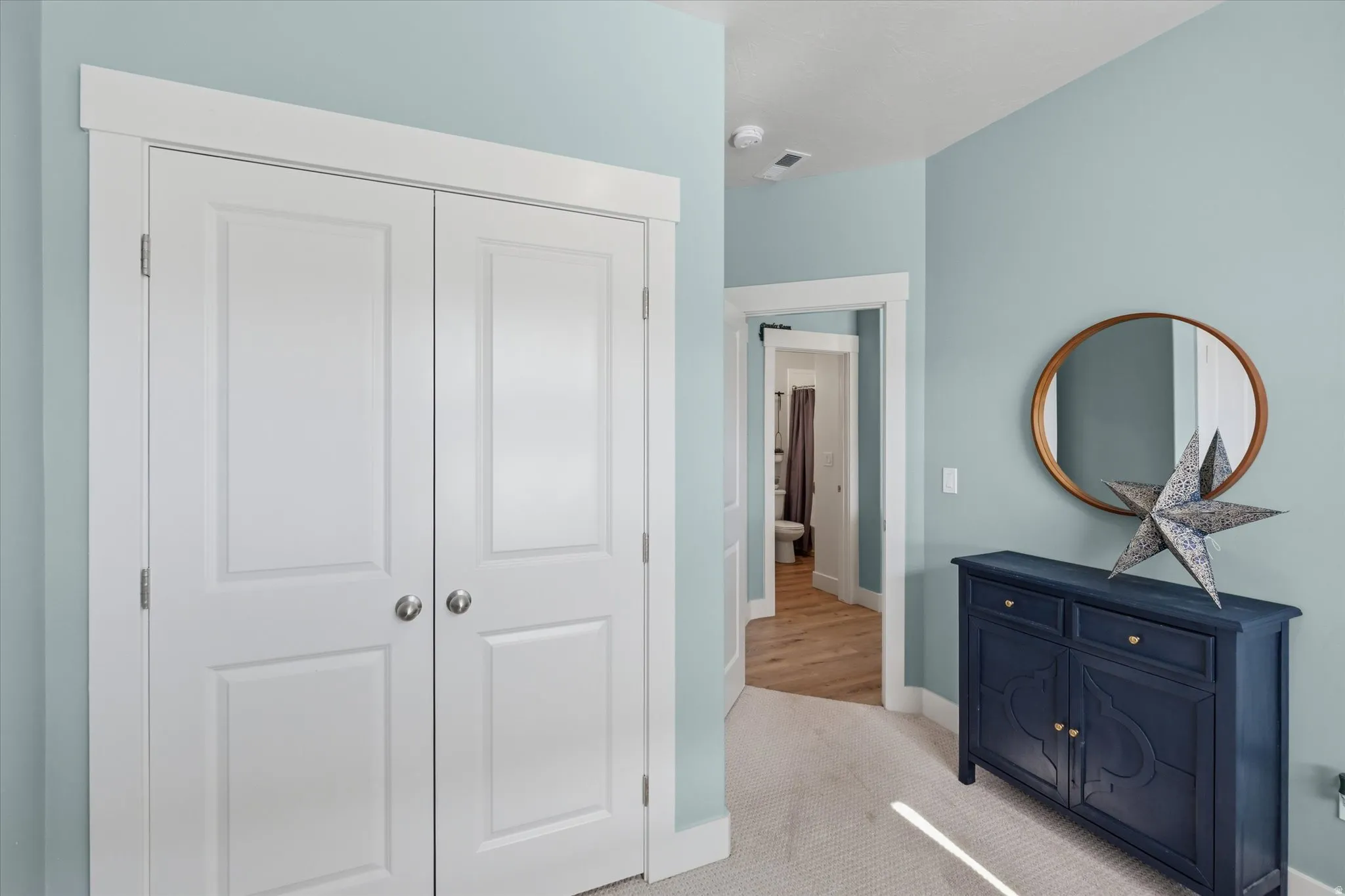 Hallway featuring light blue walls, white trim, and neutral carpet flooring