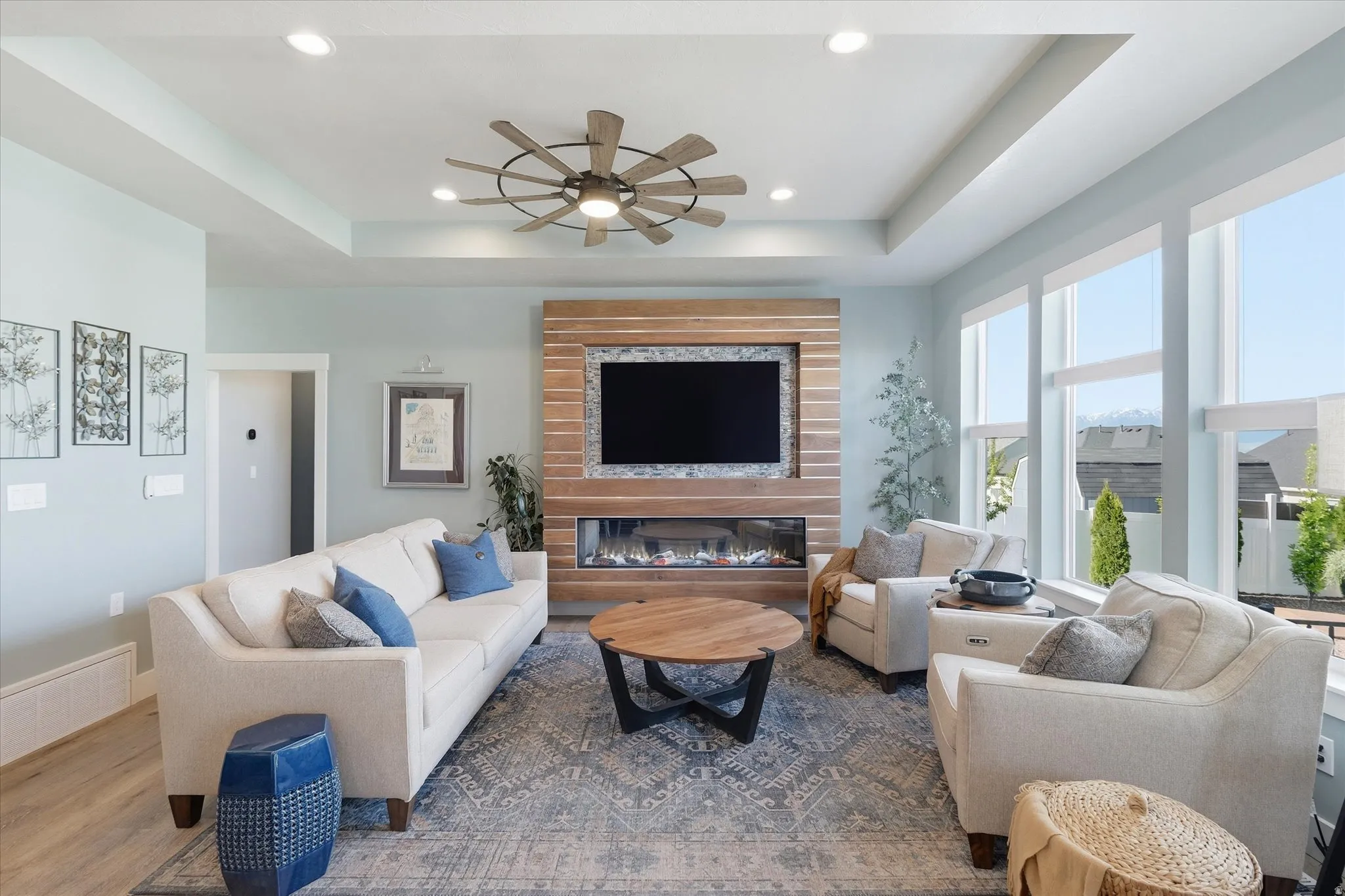 Spacious living area featuring a wood-panel accent wall, built-in linear fireplace, recessed lighting, and large windows