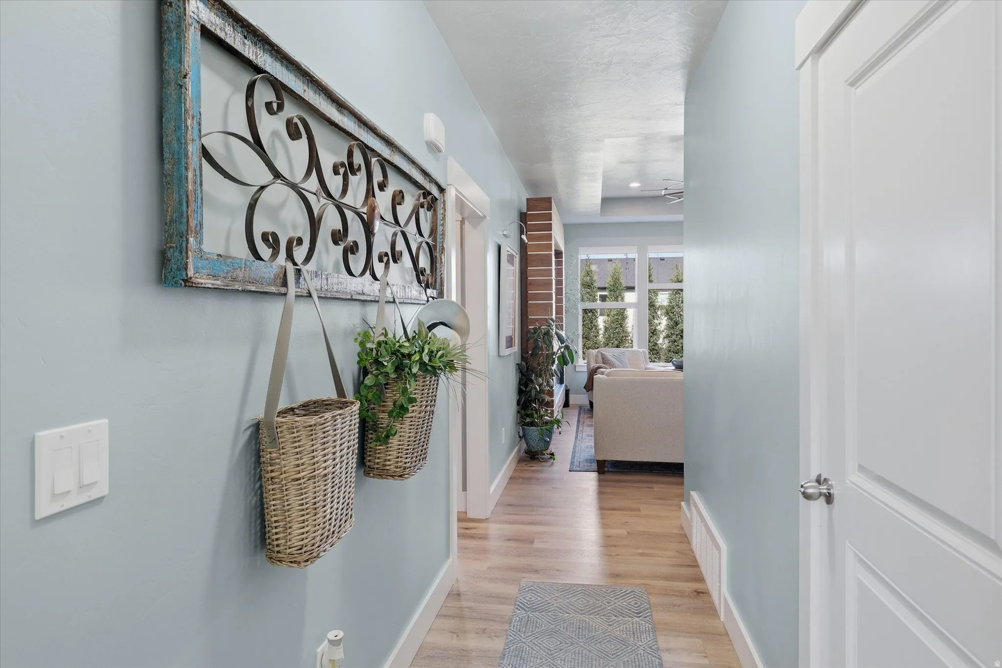 Hallway featuring wood-finish flooring, light blue wall tones, white trim, and a contemporary light fixture