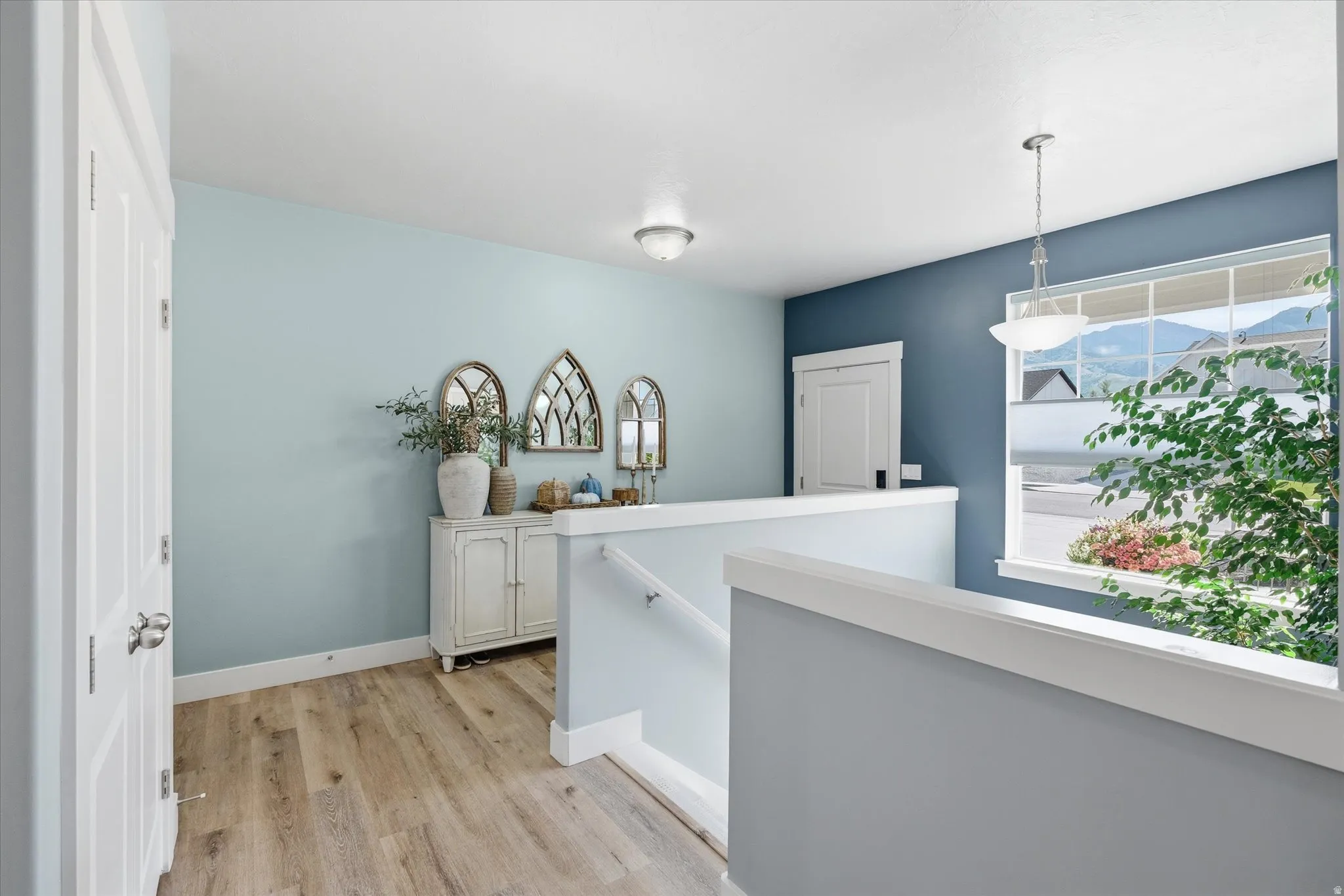 Upper-level landing featuring wood-finish flooring, a window with mountain scenery, and contrasting wall colors