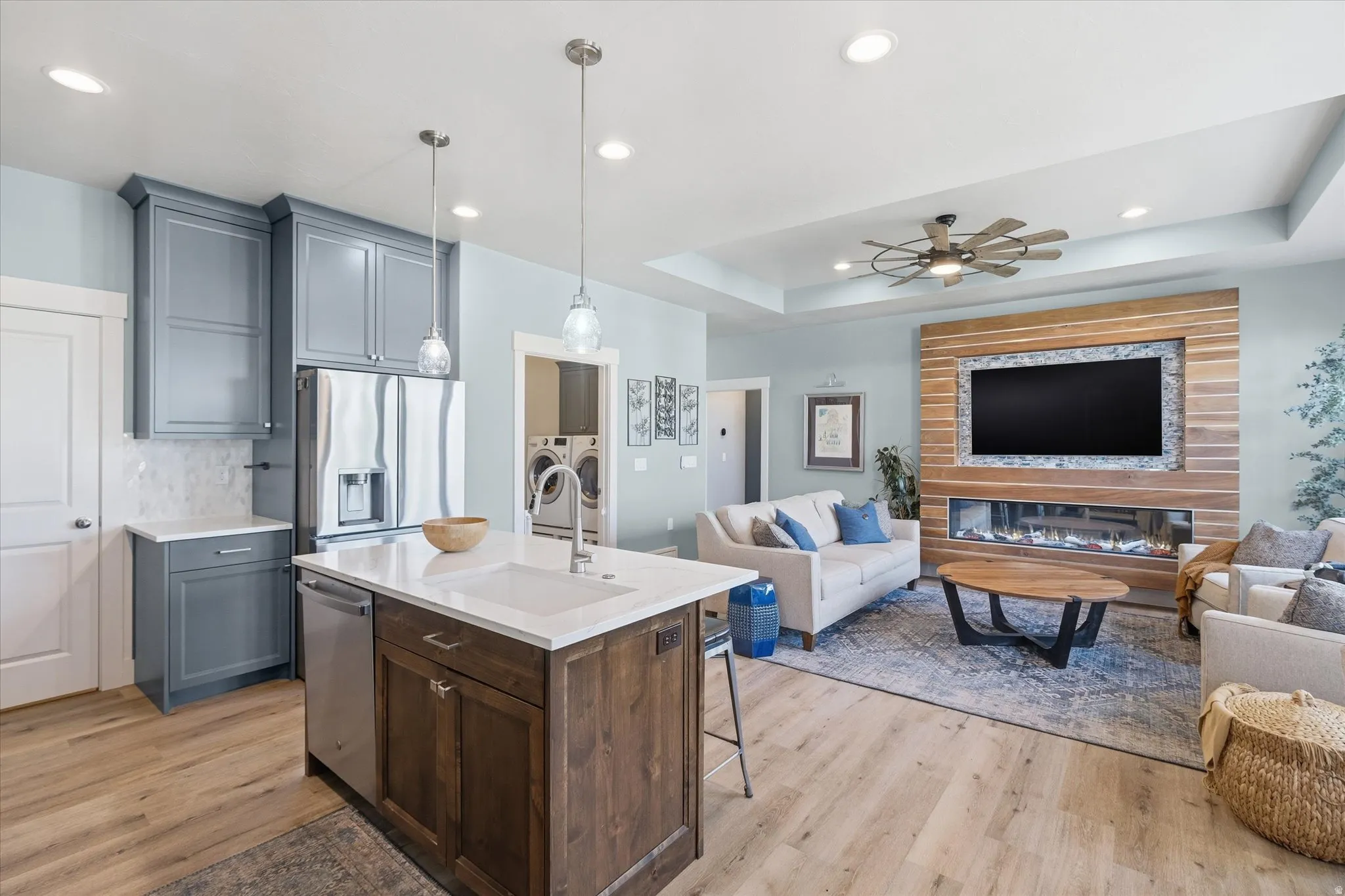 Open concept living space featuring a kitchen island with sink, stainless steel appliances, and wood-finish flooring