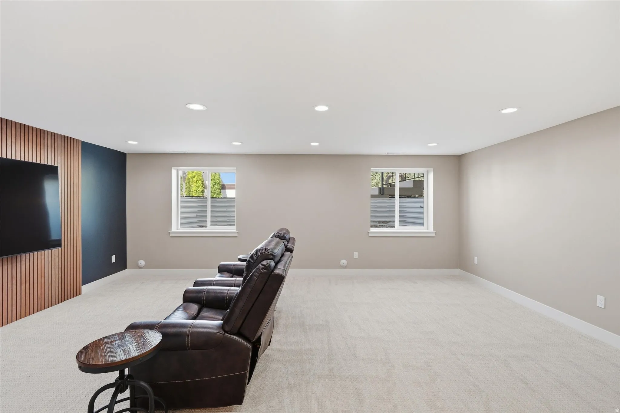 Spacious room featuring light-colored carpeting, recessed lighting, and two windows