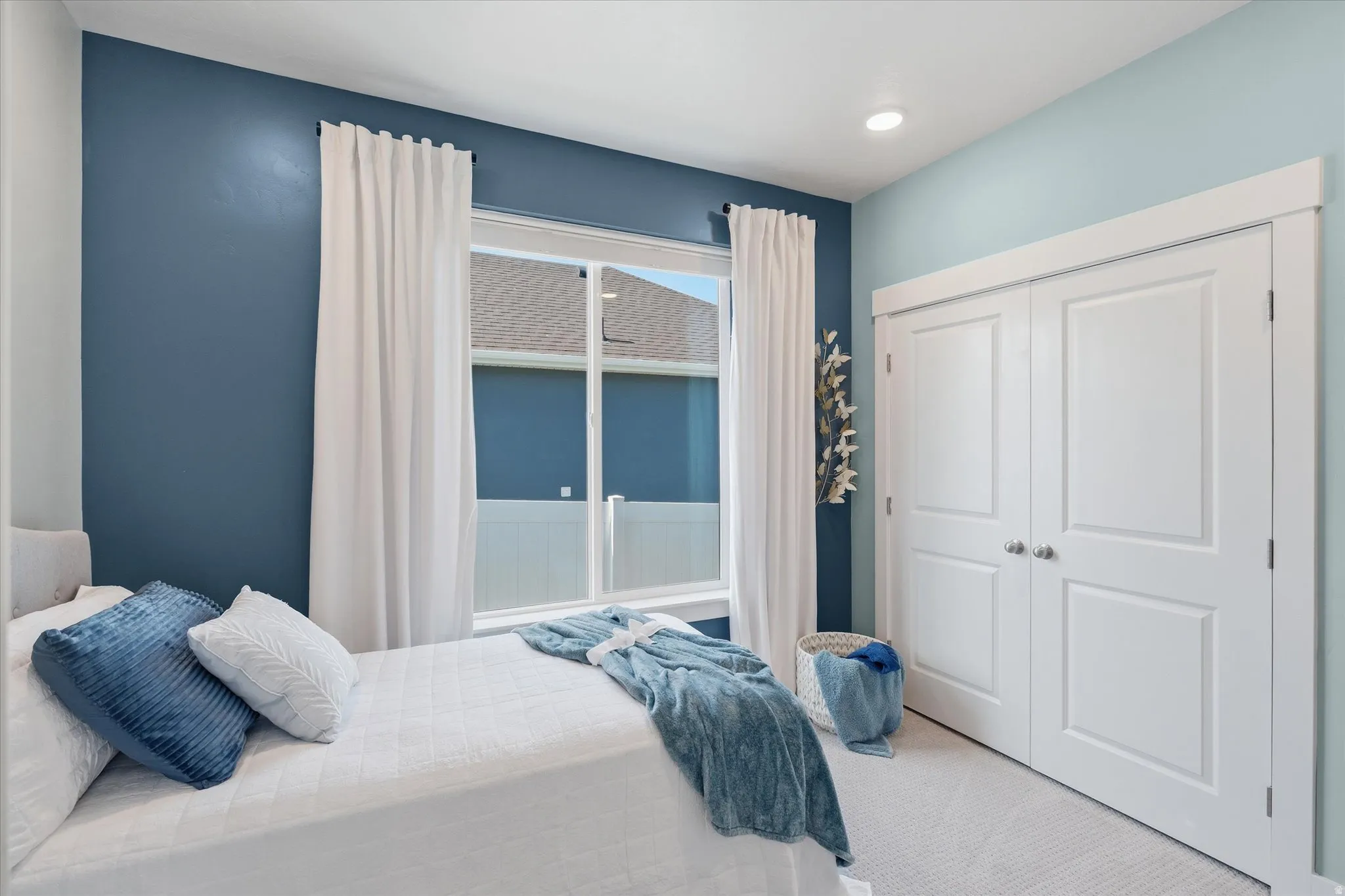 Bedroom featuring a large window with white curtain panels, two-tone wall paint, recessed lighting, and a double-door closet with paneling and brushed nickel hardware