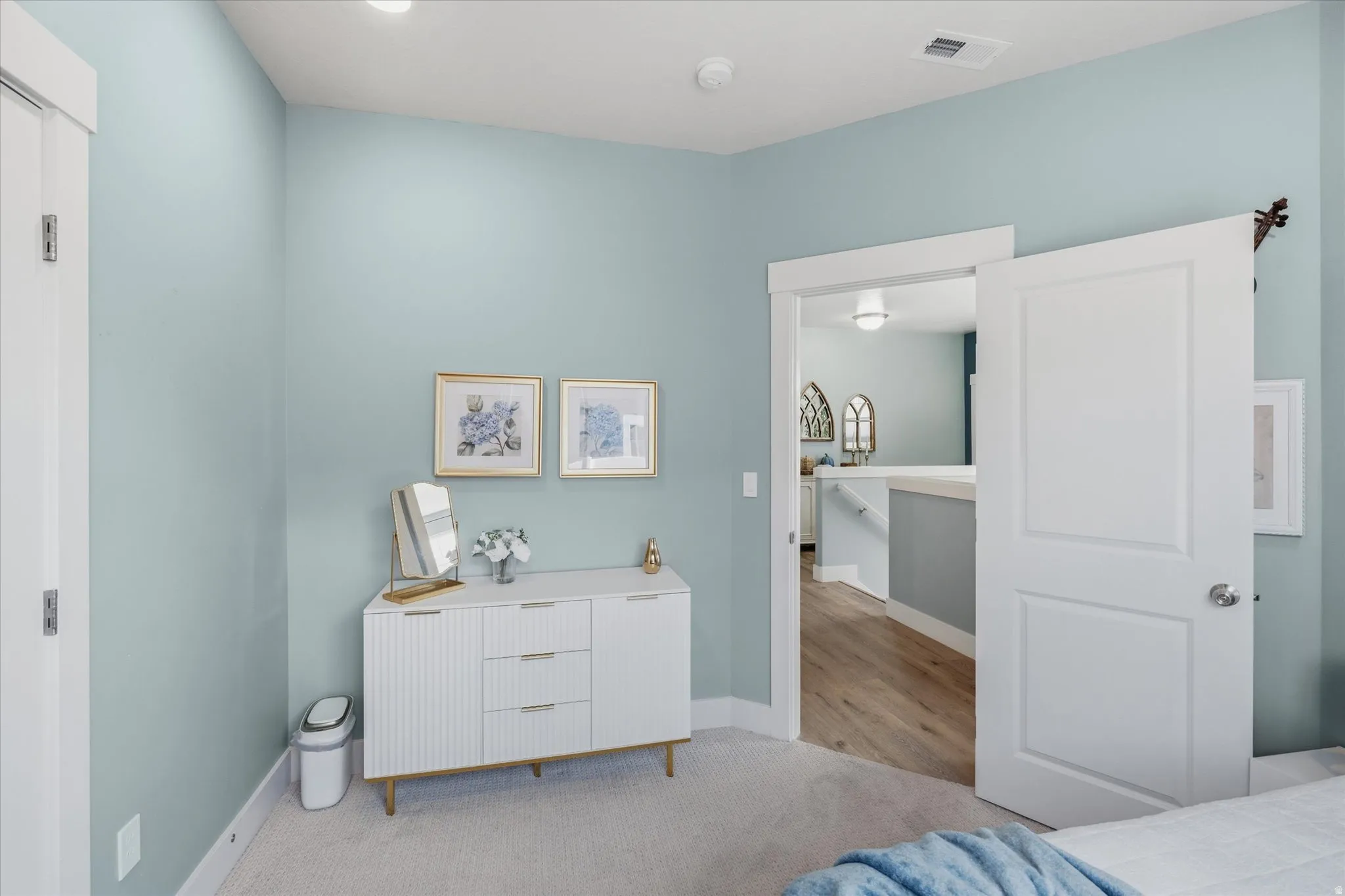 Spacious room with light blue walls, soft carpet flooring, and white trim