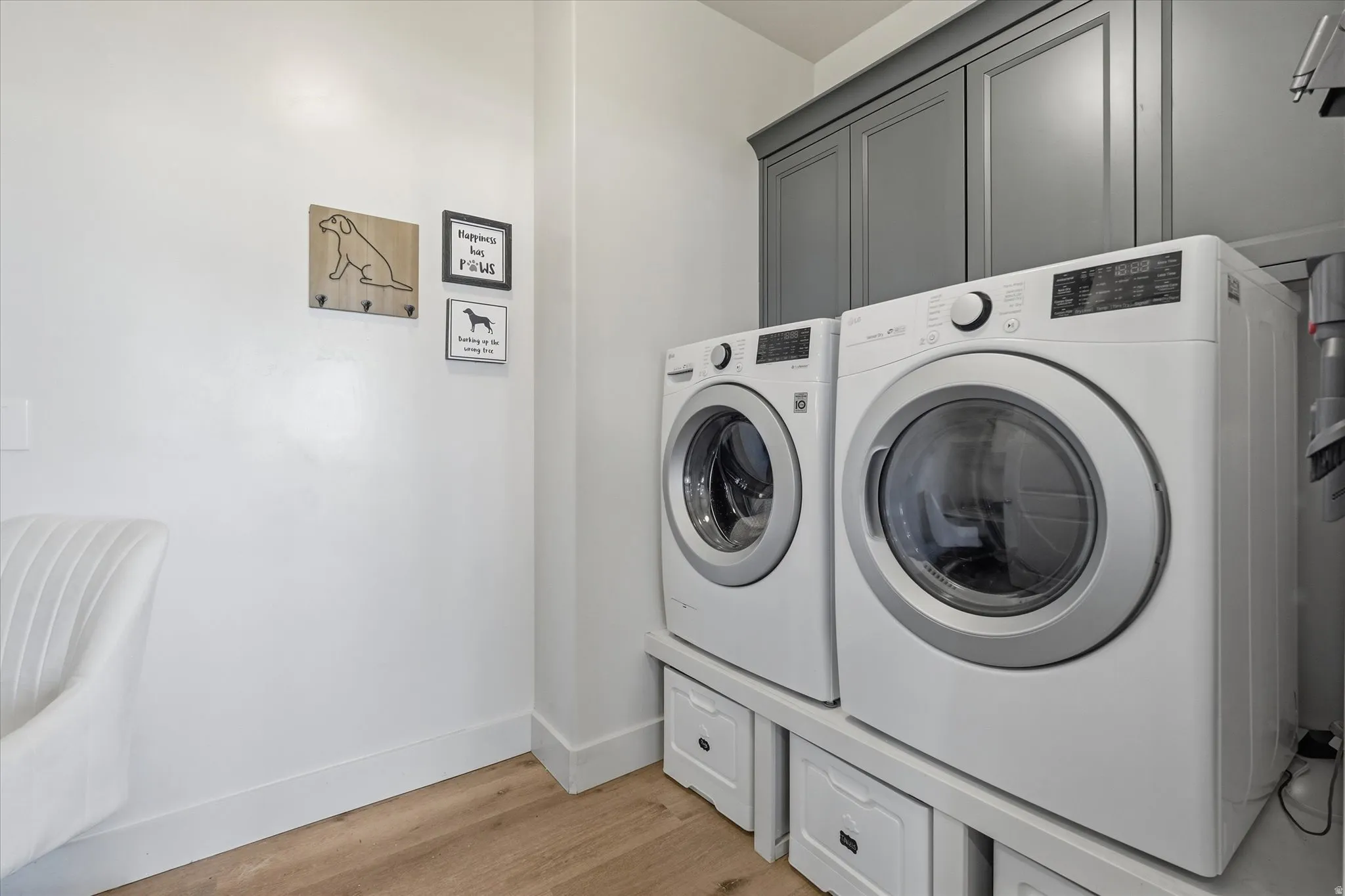 Dedicated laundry space featuring a white front-load washer and dryer set, custom built-in cabinetry, and wood-finish flooring