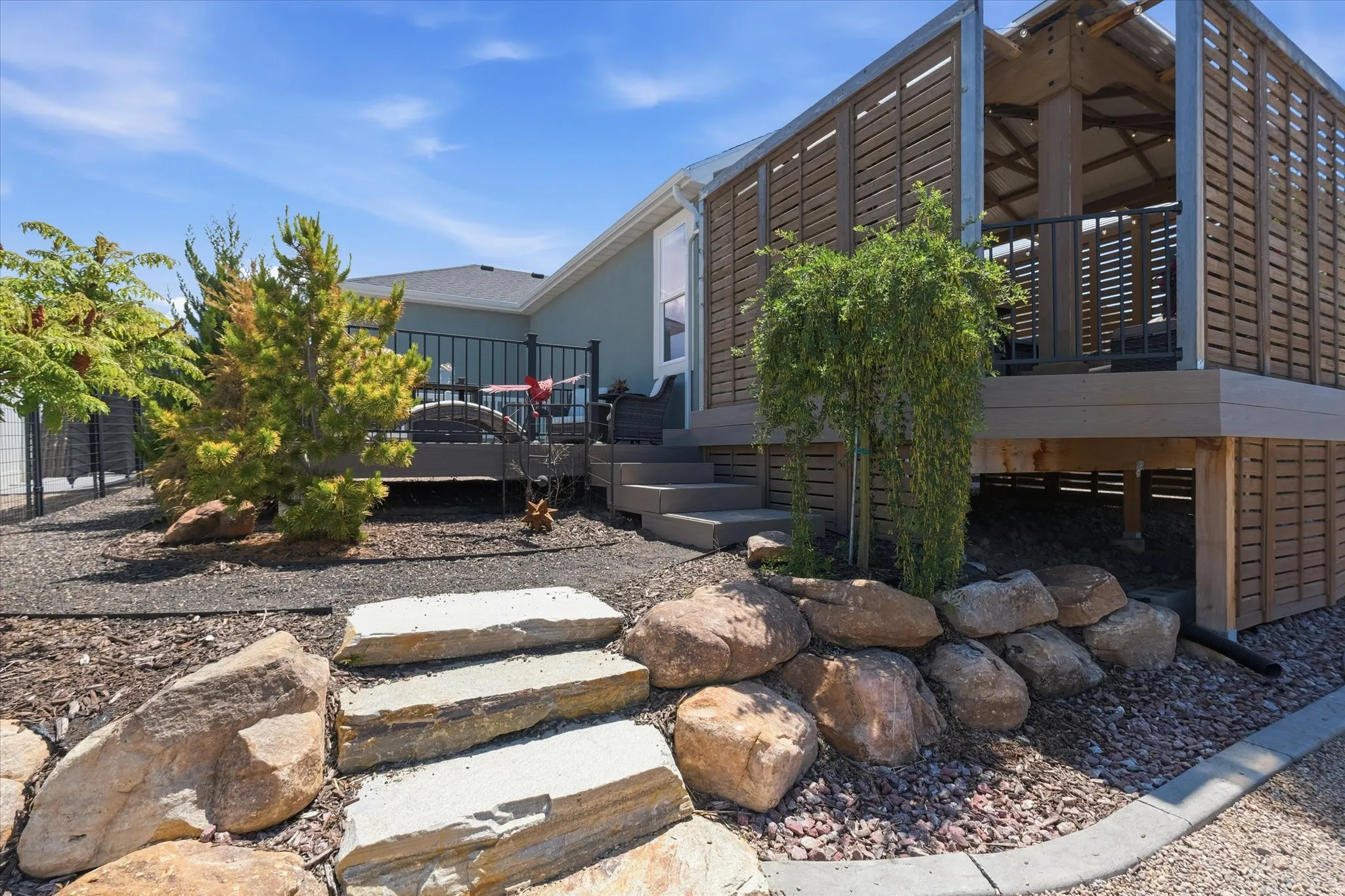 Elevated deck with slatted wood-look privacy screens, integrated steps, and black metal railings