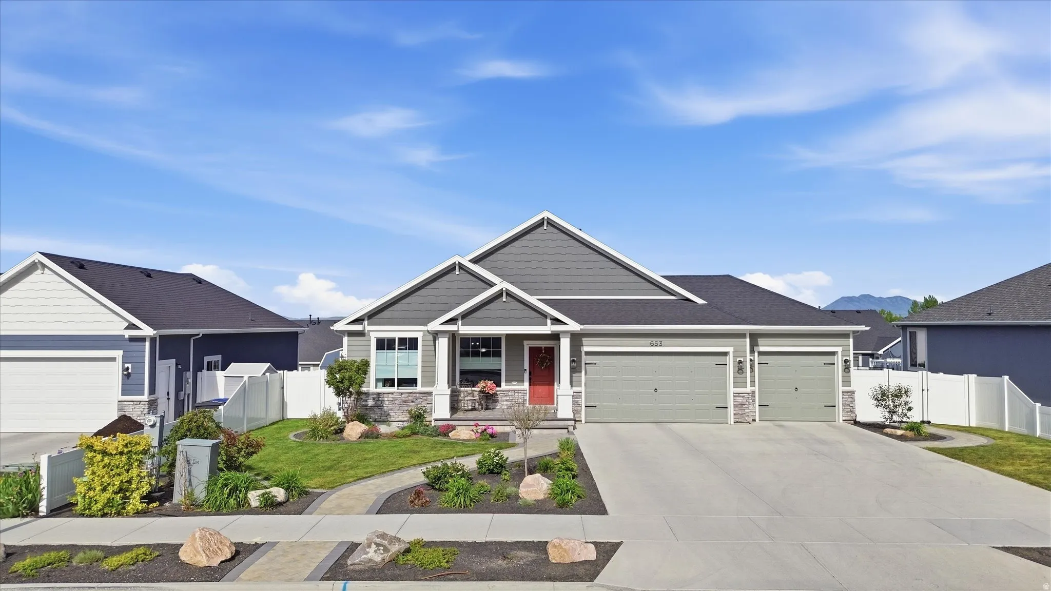Ranch-style exterior featuring gray siding, stone accents, and a contrasting red entry door