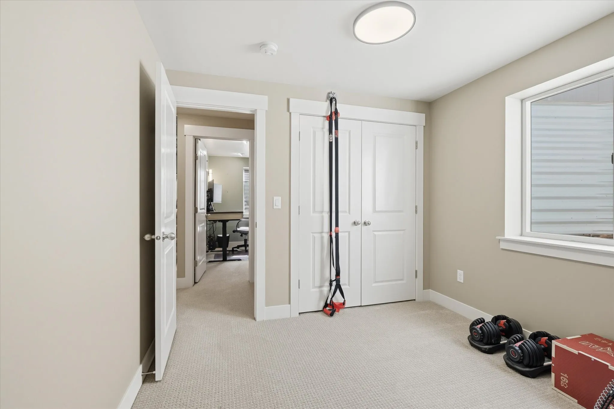 Interior room featuring neutral wall paint, light-colored carpeting, a window with white trim, and a flush-mount ceiling light fixture