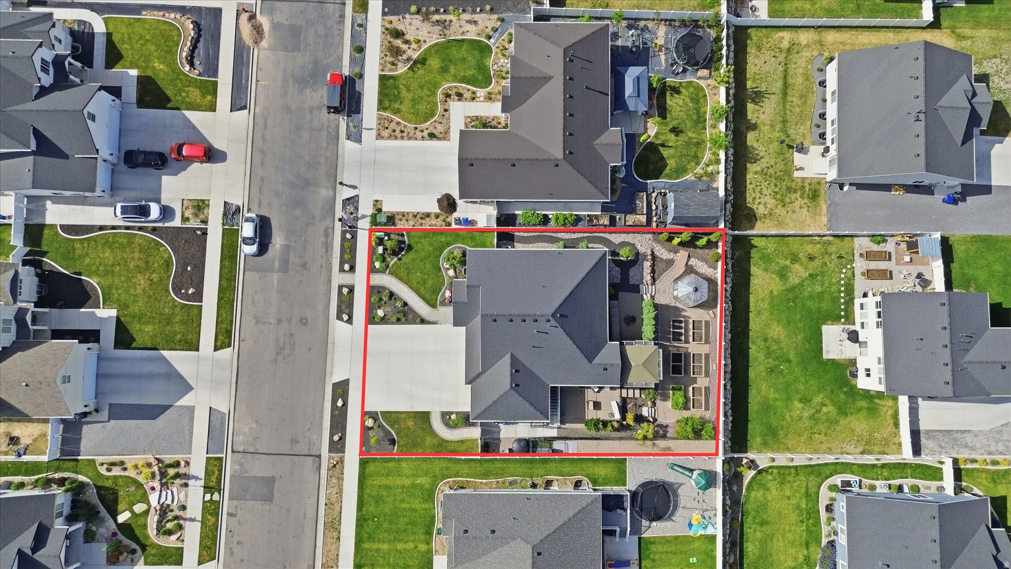 Manicured property featuring a dark-toned roof, concrete driveway, and a paved patio area