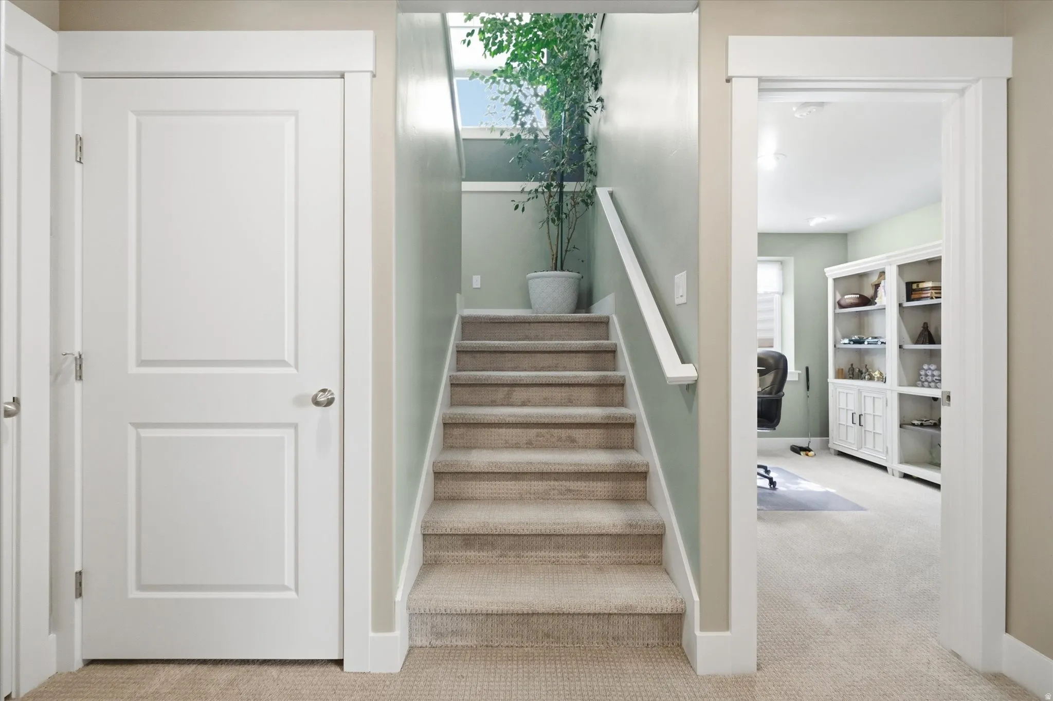 Carpeted staircase with painted handrail and balusters, featuring a prominent window