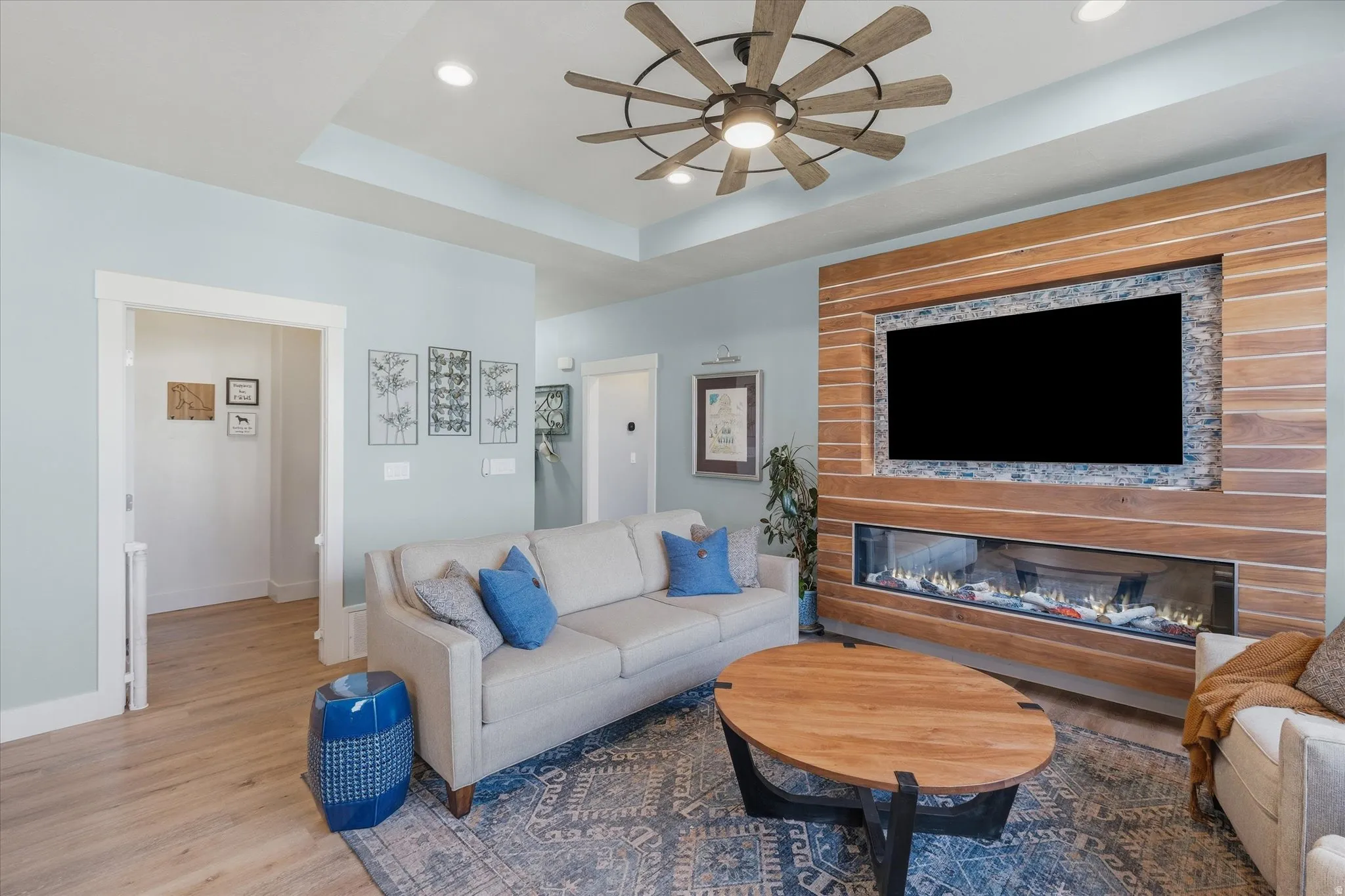 Living space featuring a multi-tone wood accent wall with a built-in linear fireplace and recessed television