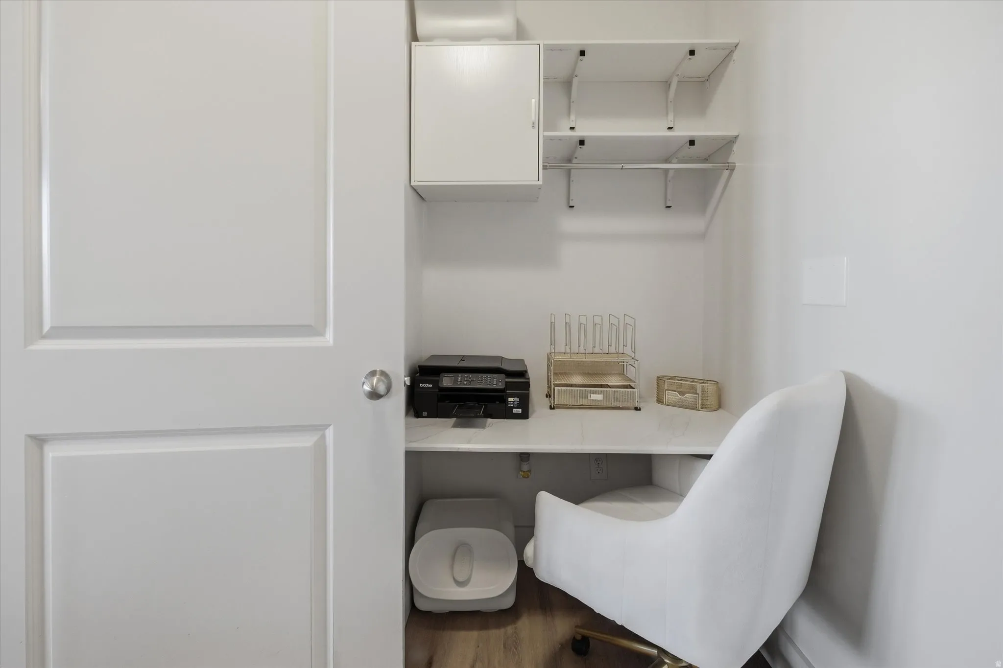 Built-in desk nook featuring a white countertop and wood-finish flooring