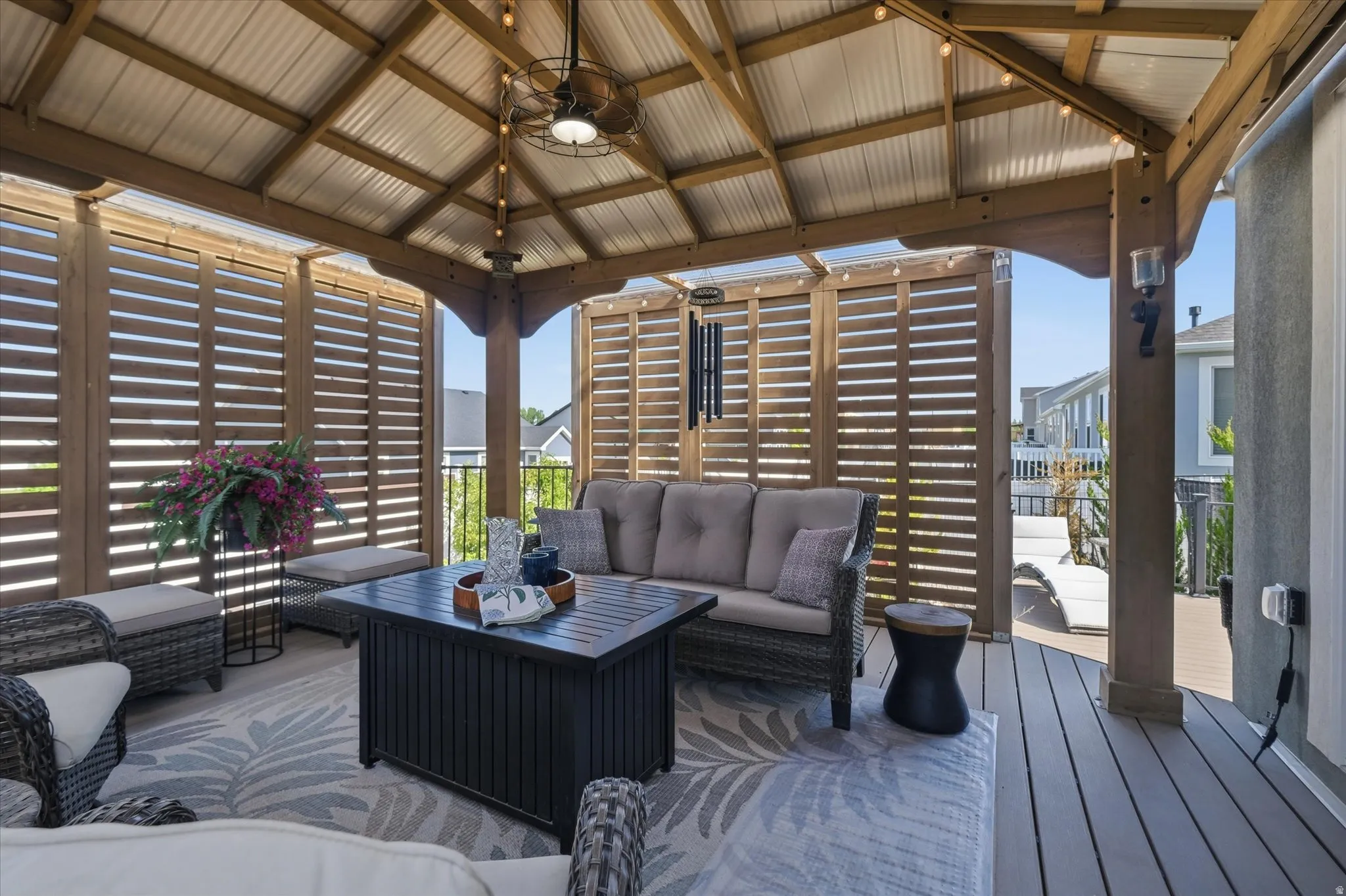 Covered outdoor living area featuring a vaulted metal roof, slatted wood privacy screens, and wood-finish decking