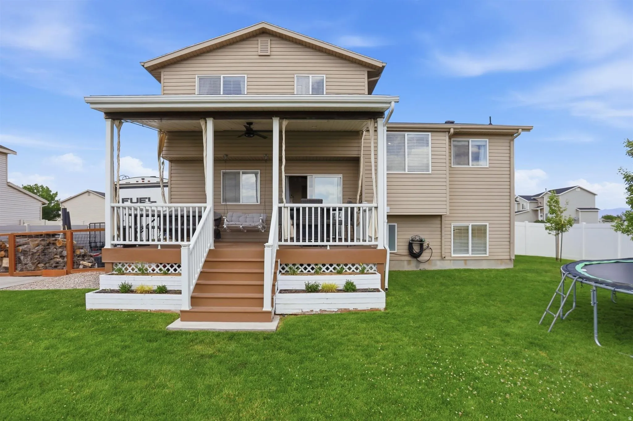 Rear exterior featuring a covered deck with white railing, wood-finish steps, and a ceiling fan